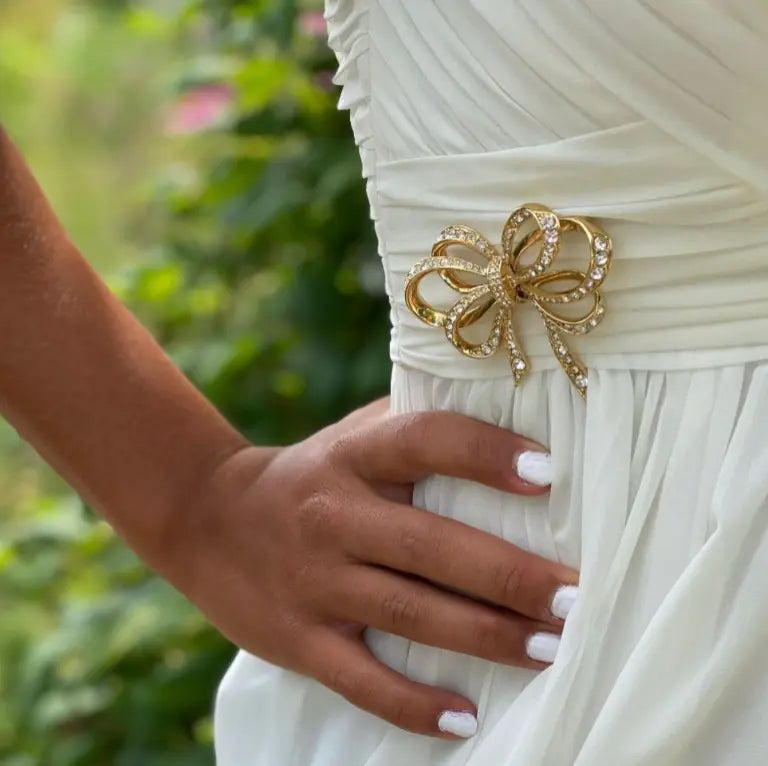 Vintage bow rhinestone brooch pinned to bridal sash.