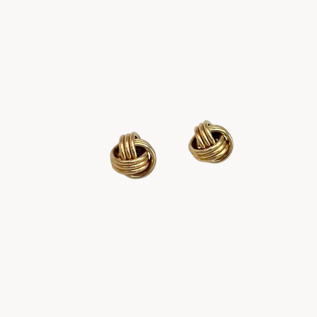 Close up view of 10K yellow gold knot stud pierced earrings, classic love knot design on white background.