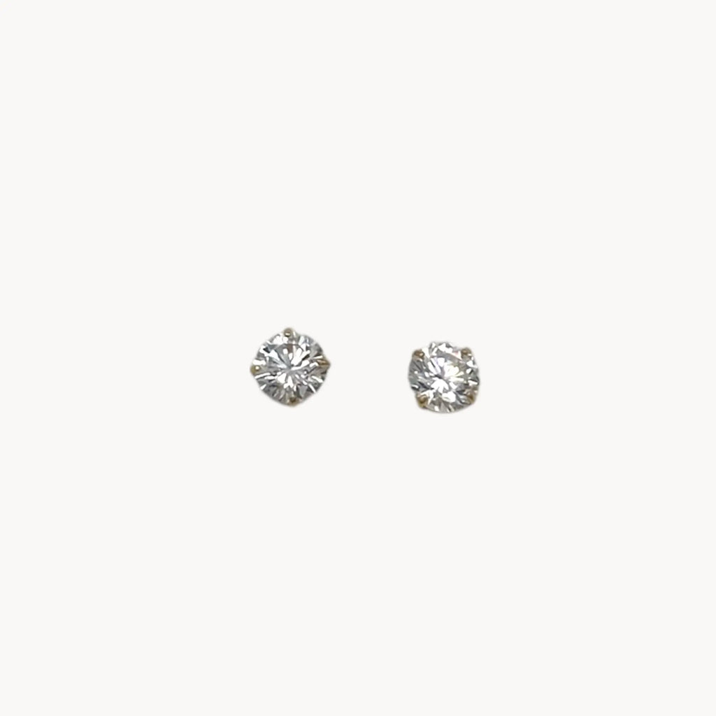 Close up of 14K yellow gold cubic zirconia solitaire stud earrings displayed on white background.