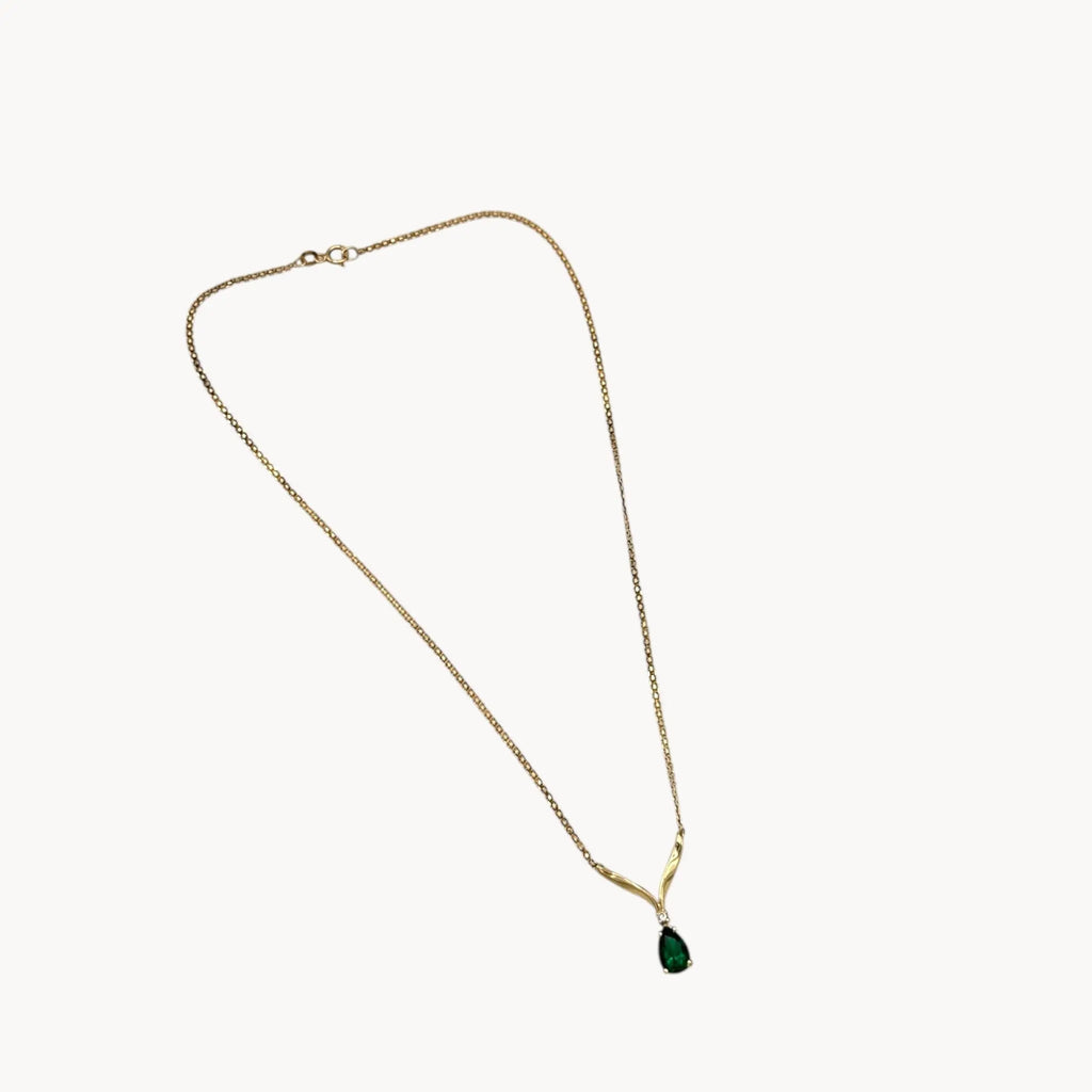 Vintage 14K yellow gold teardrop green spinel and diamond pendant necklace on white background.