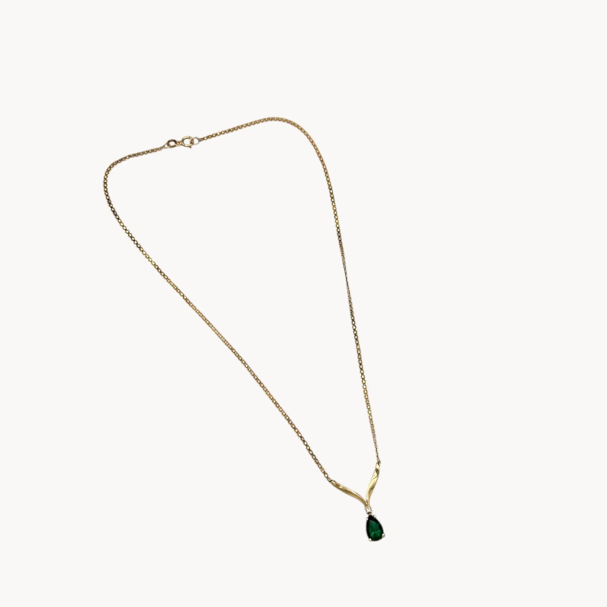 Vintage 14K yellow gold teardrop green spinel and diamond pendant necklace on white background.
