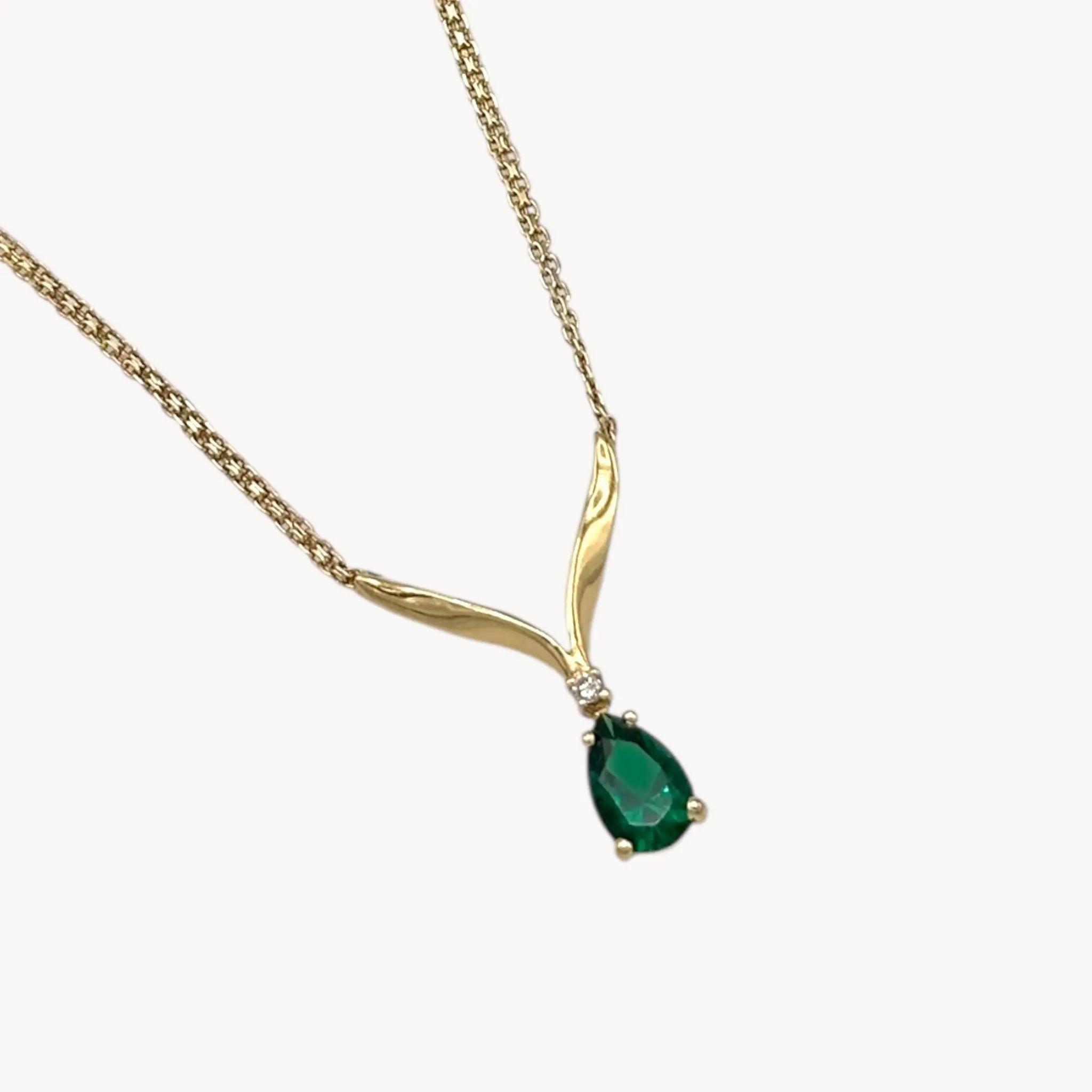 Close up of pendant of Vintage 14K yellow gold teardrop green spinel and diamond pendant necklace on white background.