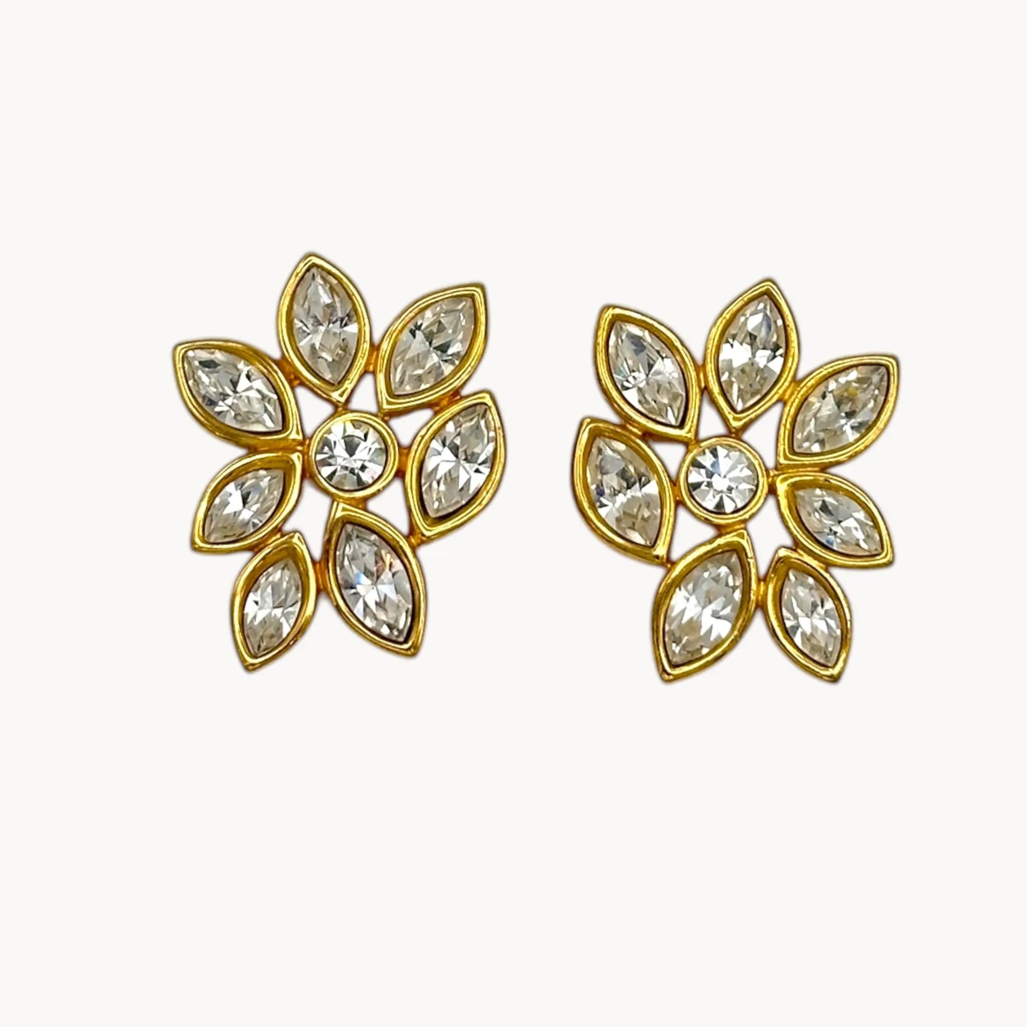 Close up view of Monet vintage gold tone pierced earrings with clear marquise rhinestones arranged in a floral pattern, elegant 1980s bridal jewelry shown on white background.