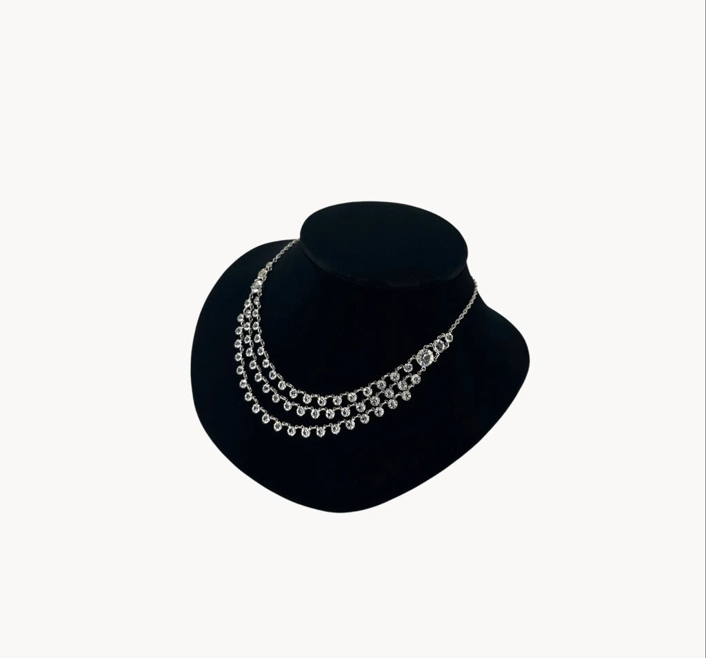 Side view of Art Deco style rhodium plated three-row crystal draped necklace on black bust.