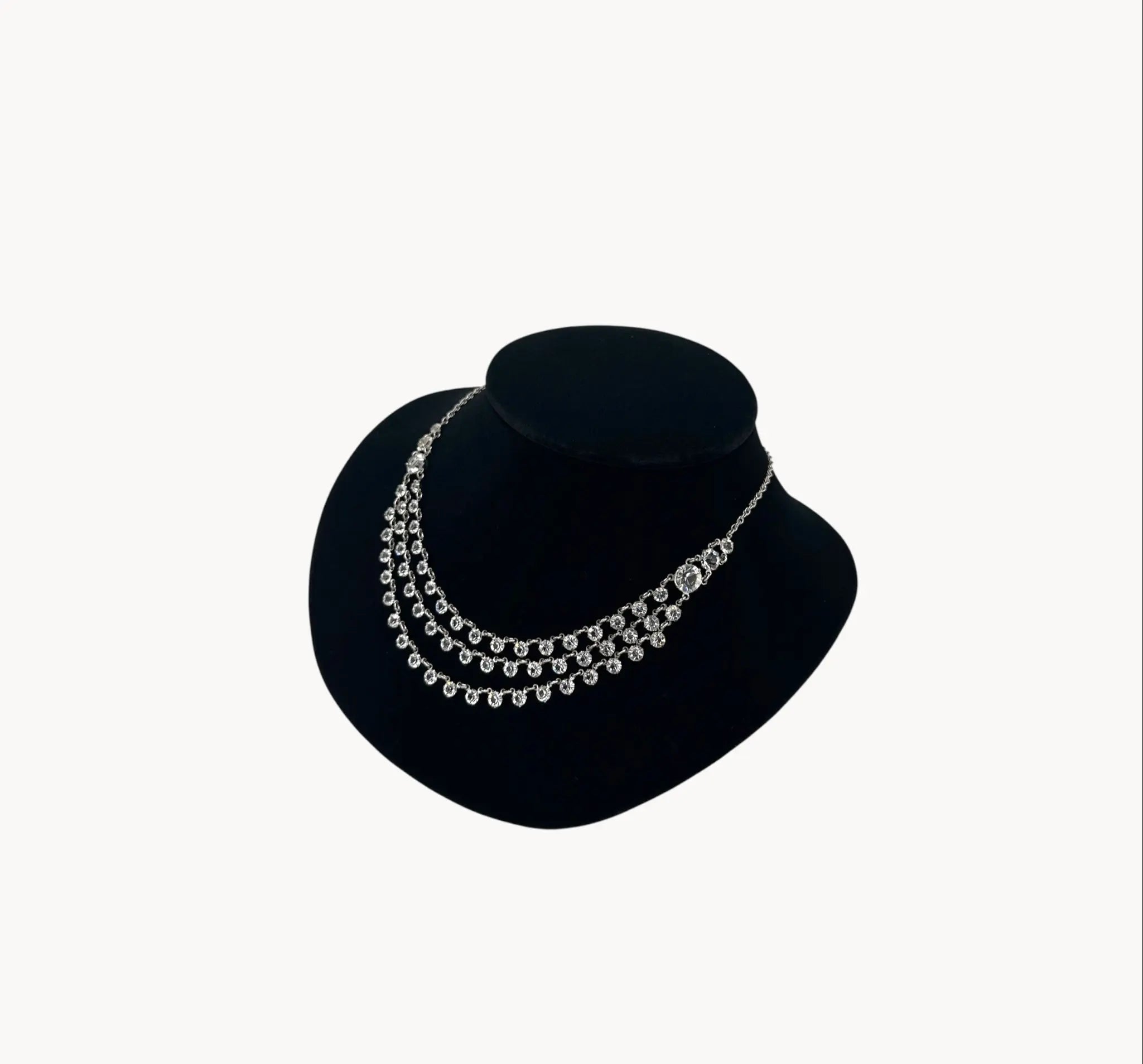 Side view of Art Deco style rhodium plated three-row crystal draped necklace on black bust.