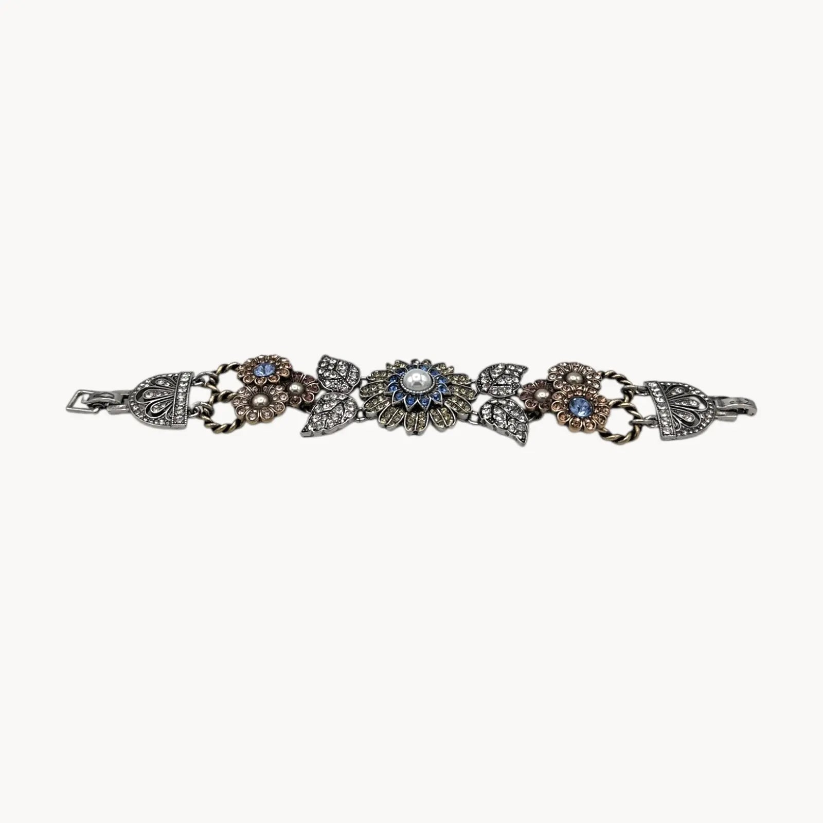 Side view of Chloe + Isabel multi-color floral rhinestone bracelet with pearls and crystal leaves on white background.