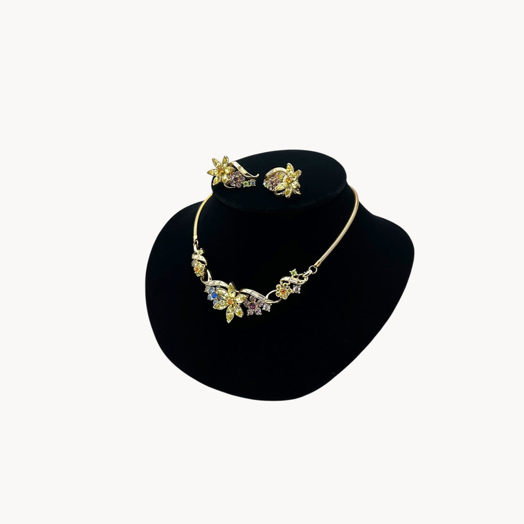Side view of Vintage Coro multi-color rhinestone necklace and clip-on earring set with floral design.
