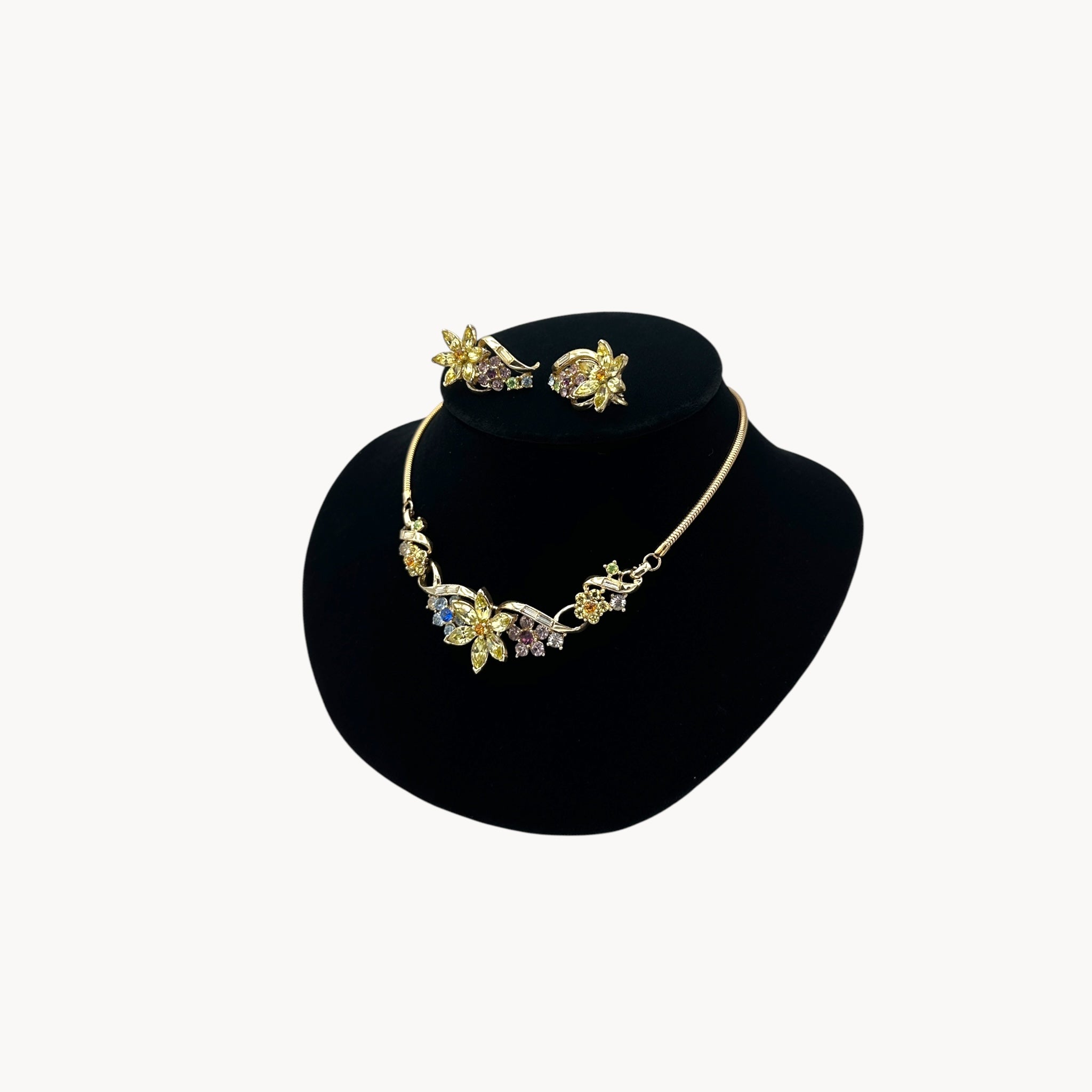 Side view of Vintage Coro multi-color rhinestone necklace and clip-on earring set with floral design.