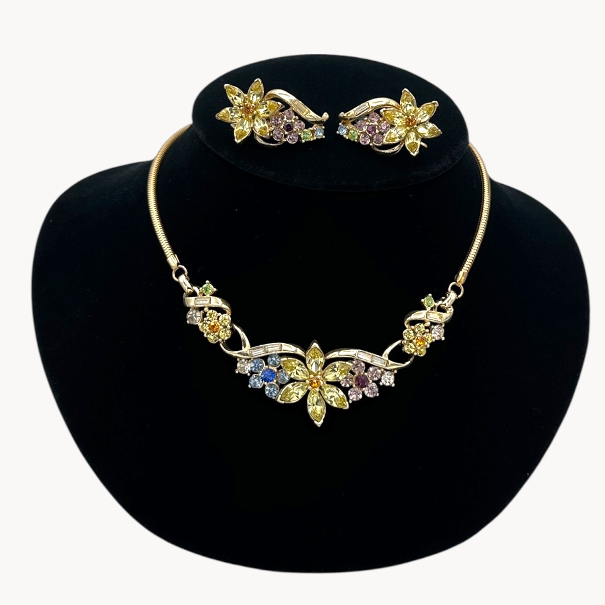 Close up view of Vintage Coro multi-color rhinestone necklace and clip-on earring set with floral design