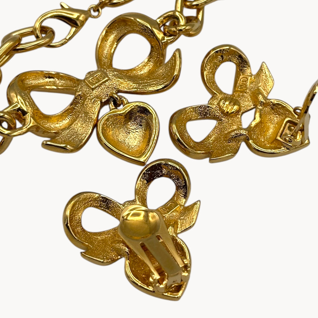 Back view of Close up view of Elizabeth Taylor gold-tone bow and pave heart bracelet and earrings on white background.