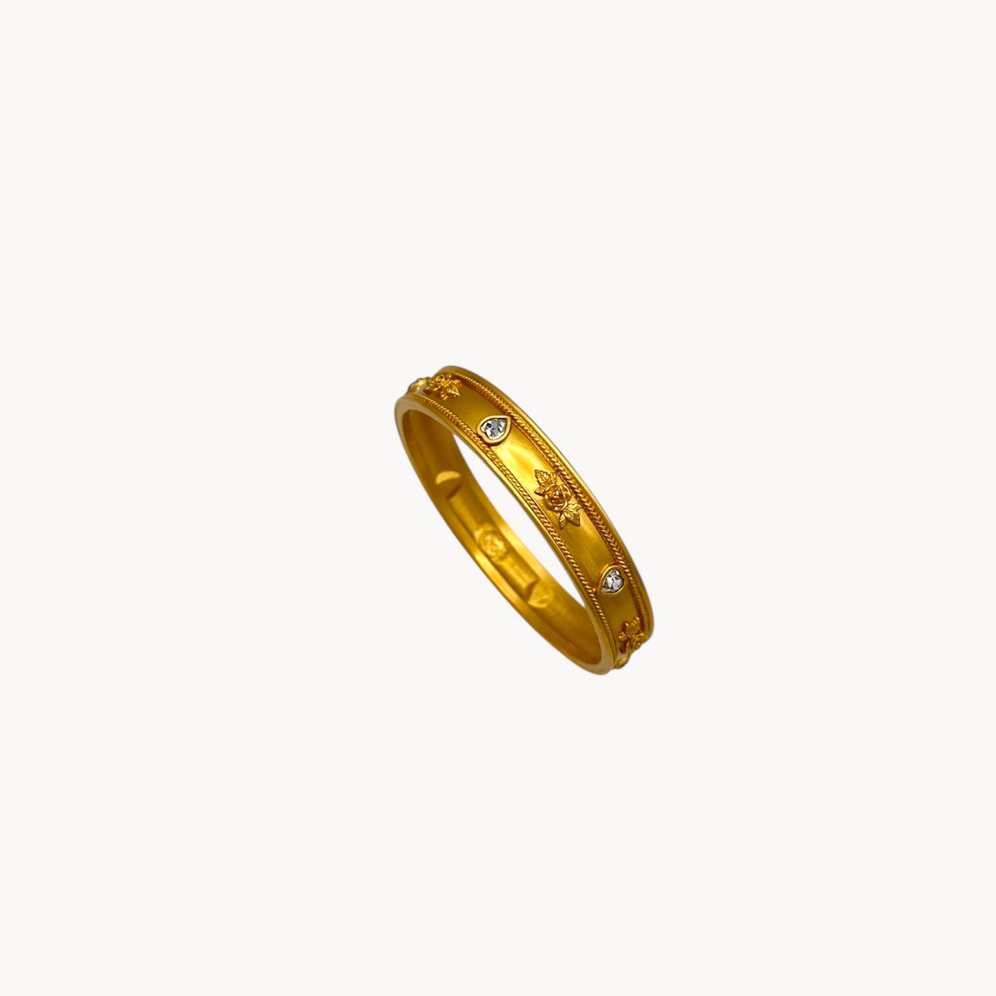 Top view of Elizabeth Taylor Love Blooms gold bangle bracelet with crystal heart and floral accents.