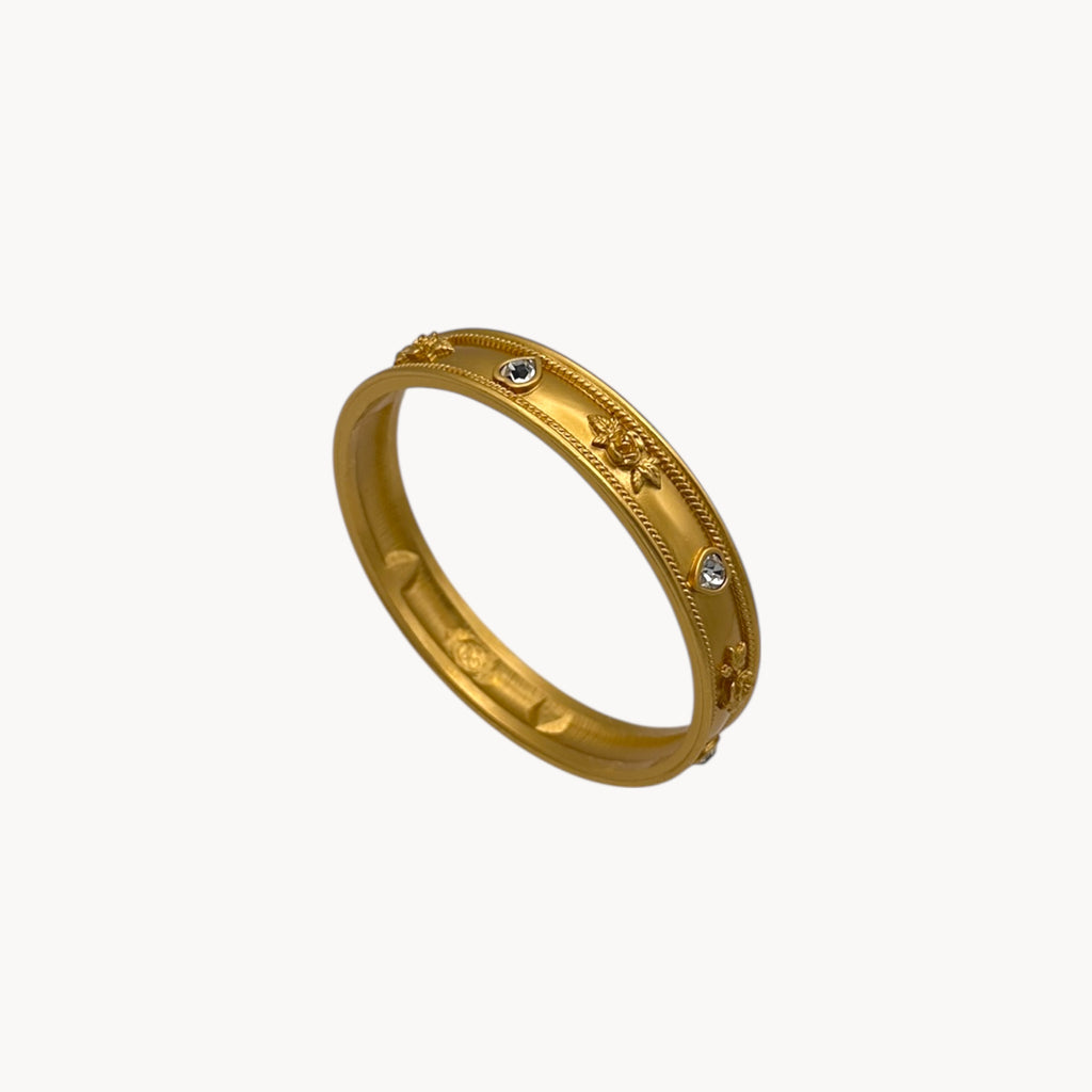Close up view of Elizabeth Taylor Love Blooms gold bangle bracelet with crystal heart and floral accents.