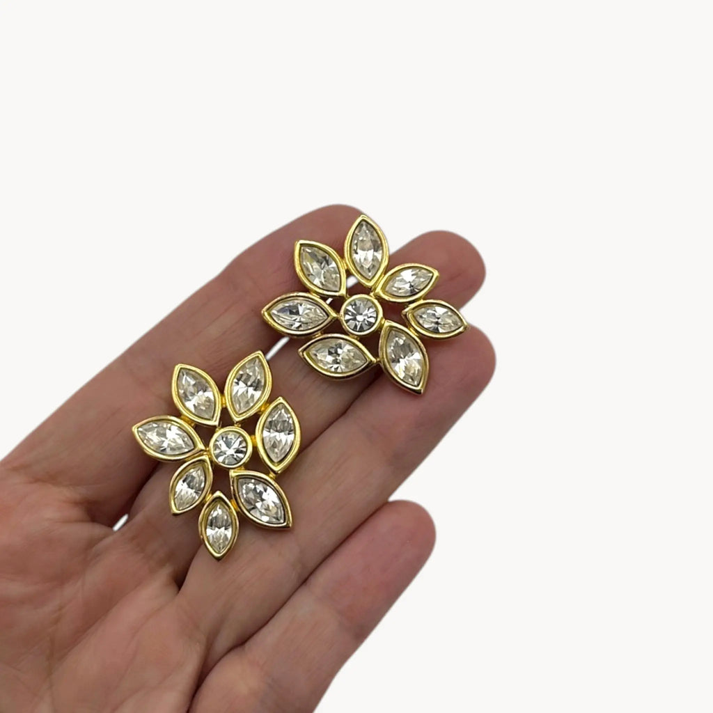 Shon on hand, Monet vintage gold tone pierced earrings with clear marquise rhinestones arranged in a floral pattern, elegant 1980s bridal jewelry shown on white background.