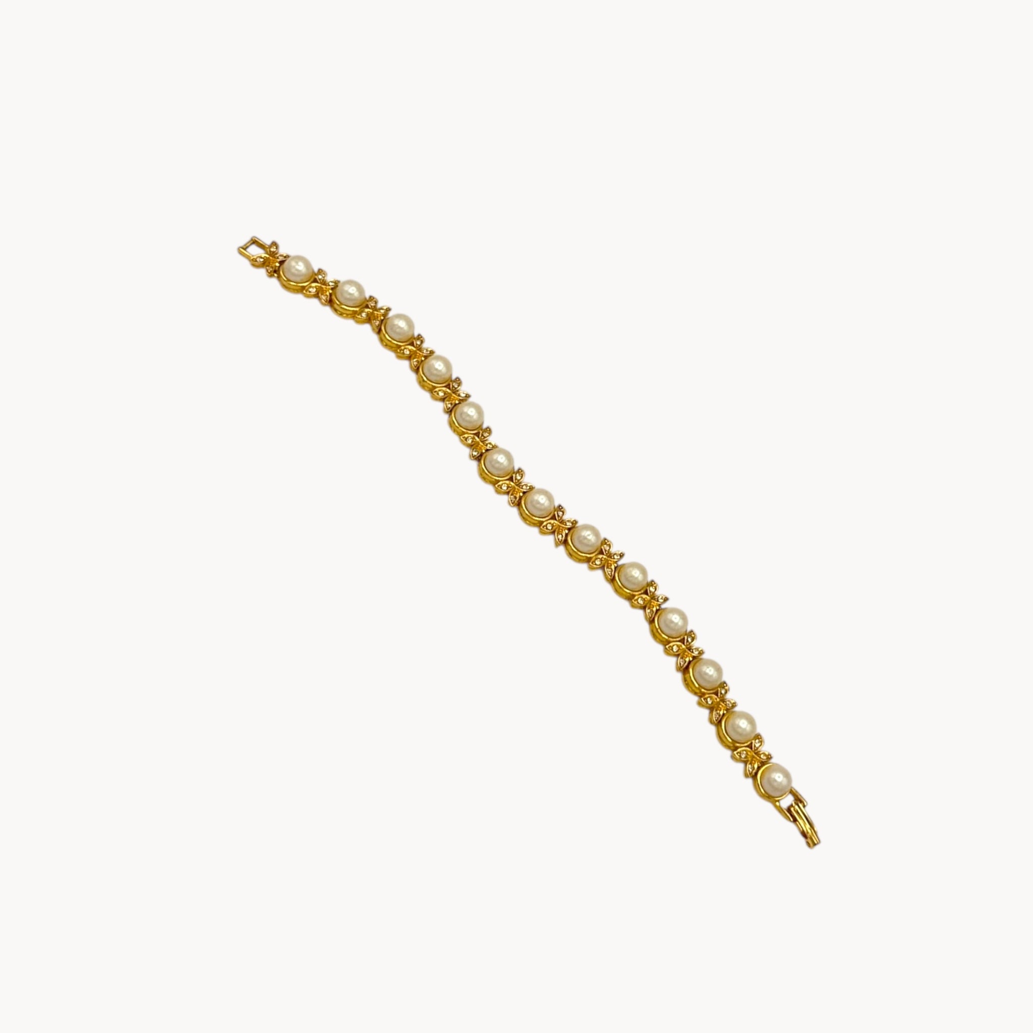 Flat lay against white of Joan Rivers gold bracelet with pearls and rhinestones.