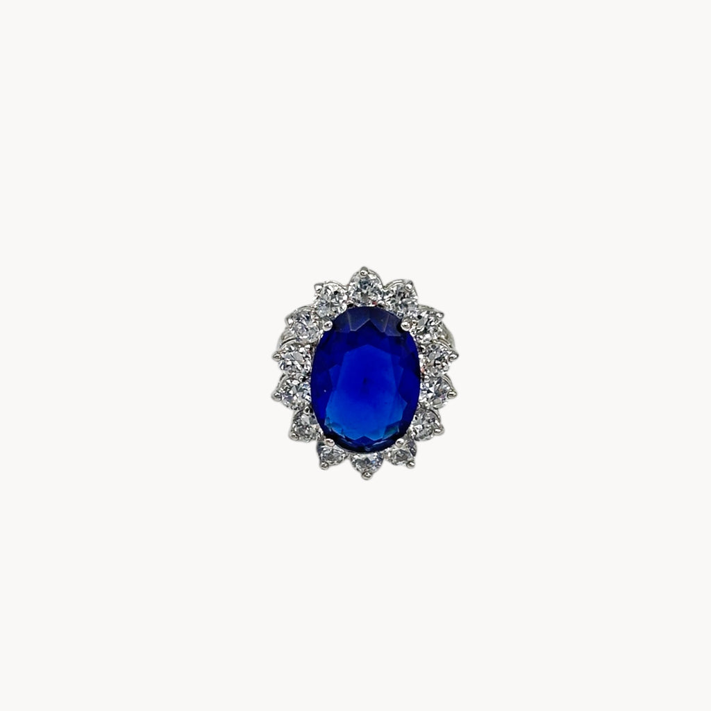 Close up view of Kenneth Jay Lane blue oval crystal cocktail ring inspired by Princess Diana’s sapphire engagement ring on white background.