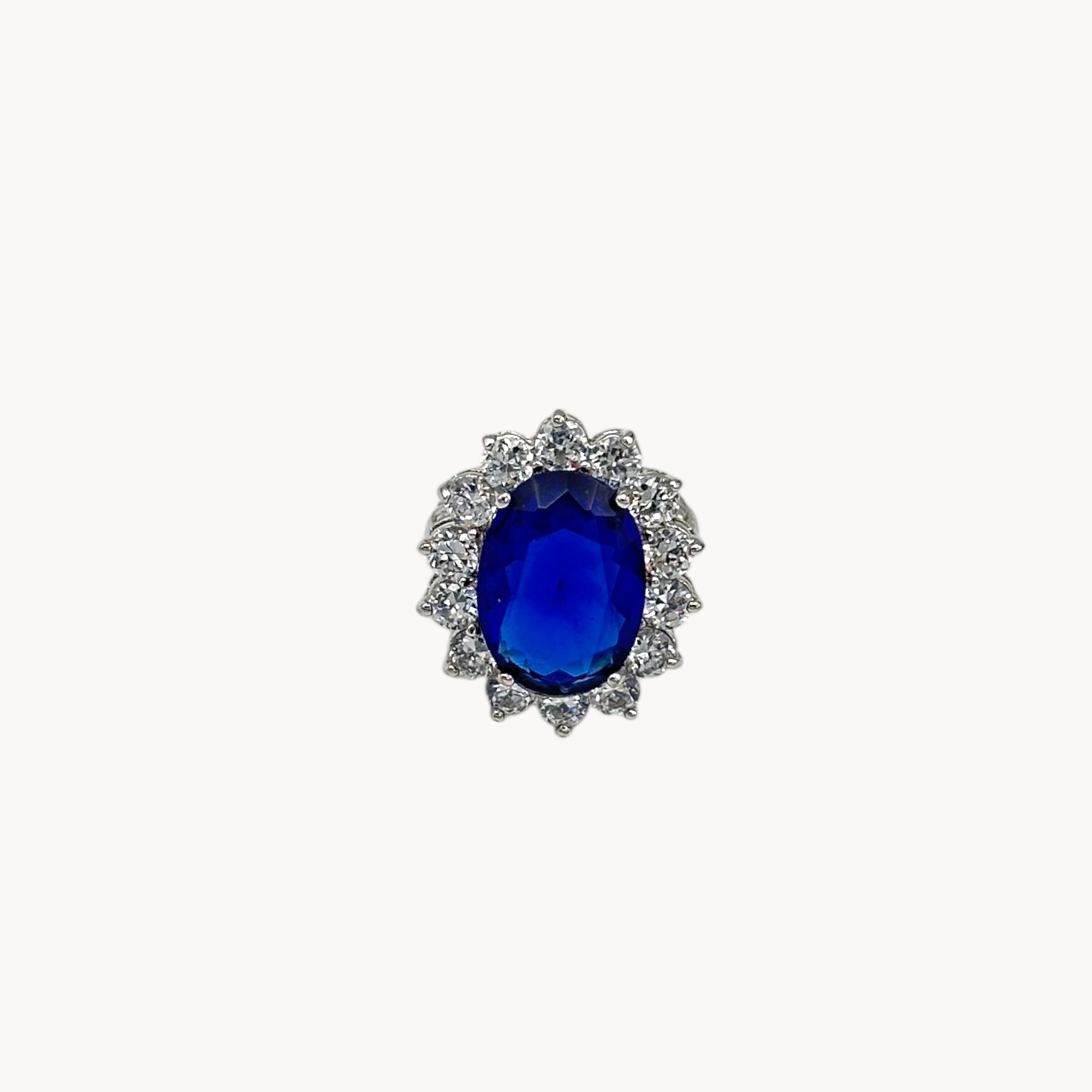 Close up view of Kenneth Jay Lane blue oval crystal cocktail ring inspired by Princess Diana’s sapphire engagement ring on white background.