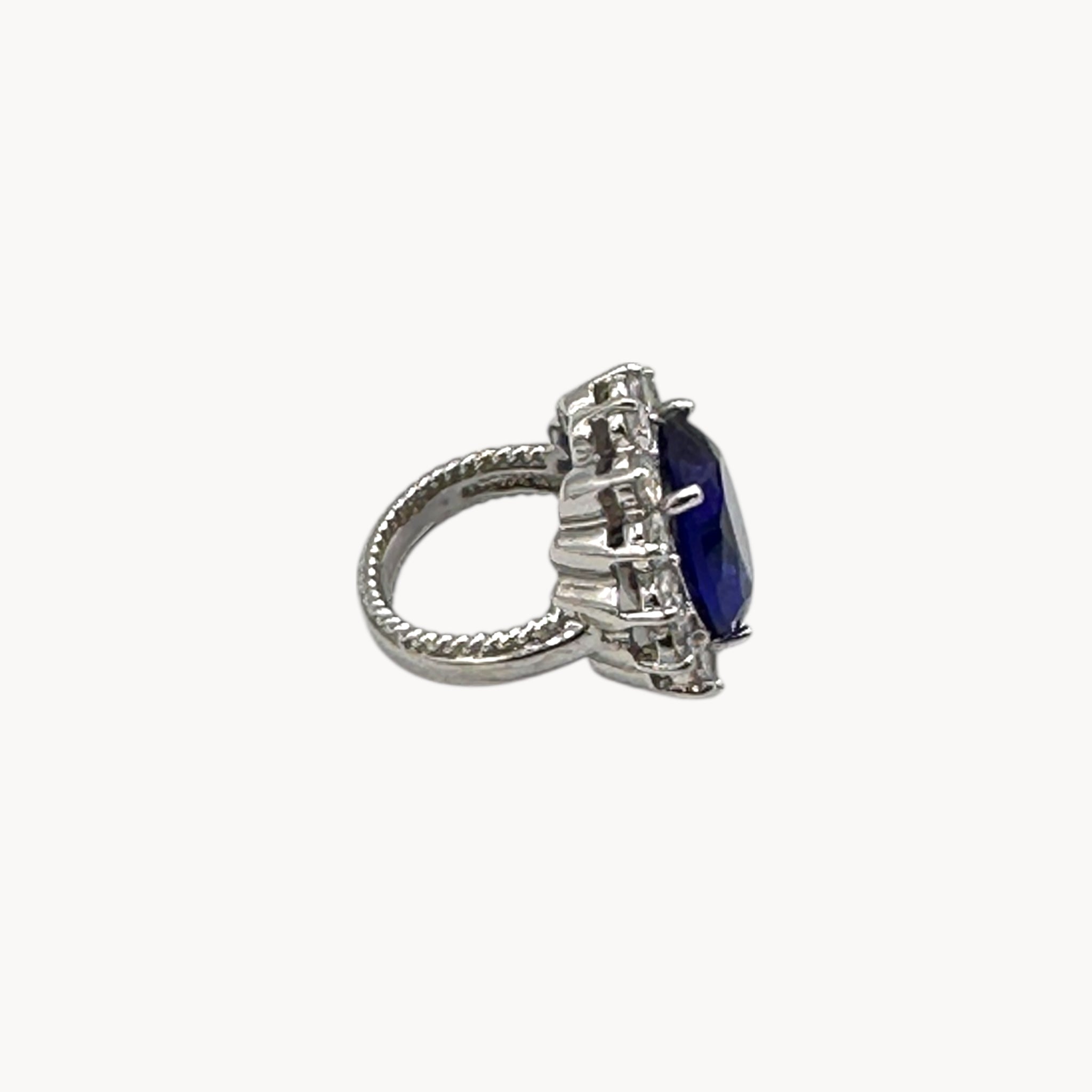 Side view of Kenneth Jay Lane blue oval crystal cocktail ring inspired by Princess Diana’s sapphire engagement ring on white background.