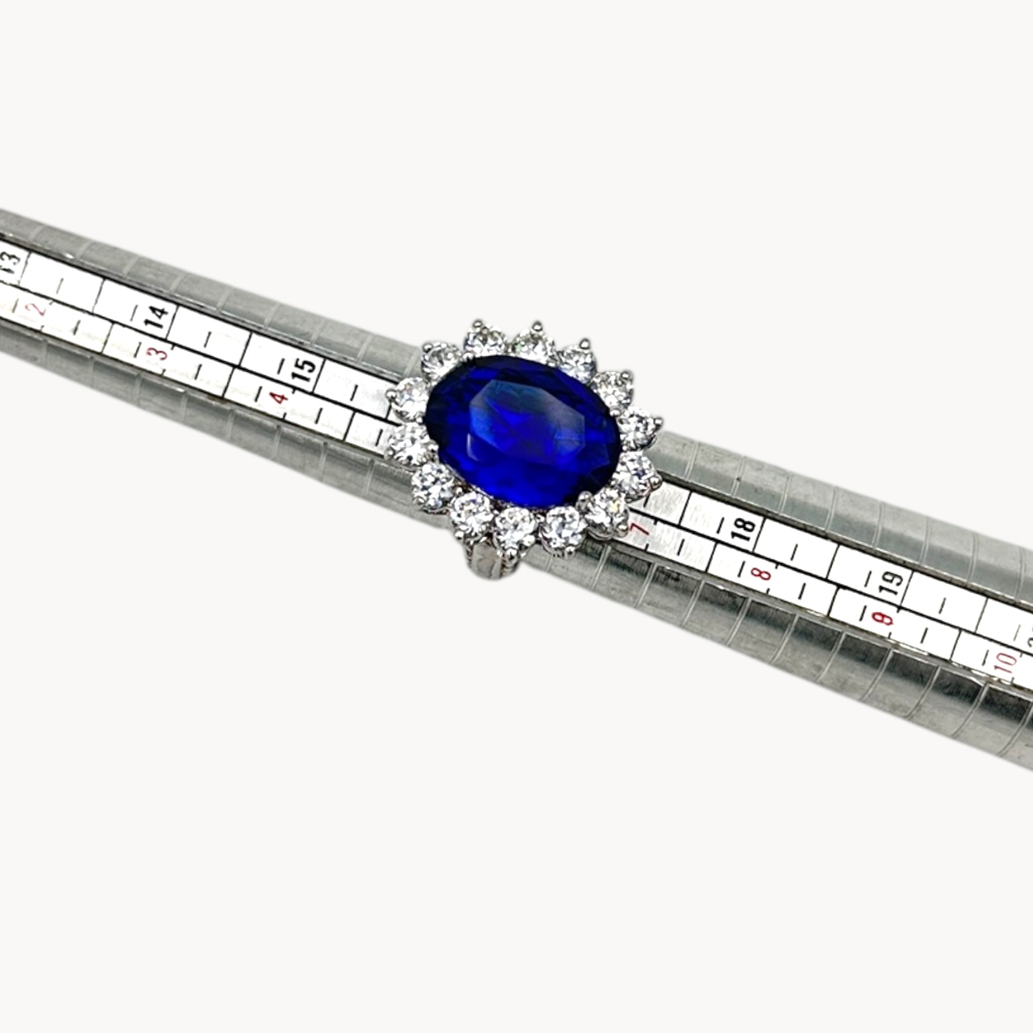 Ring view on sizer of Kenneth Jay Lane blue oval crystal cocktail ring inspired by Princess Diana’s sapphire engagement ring on white background.