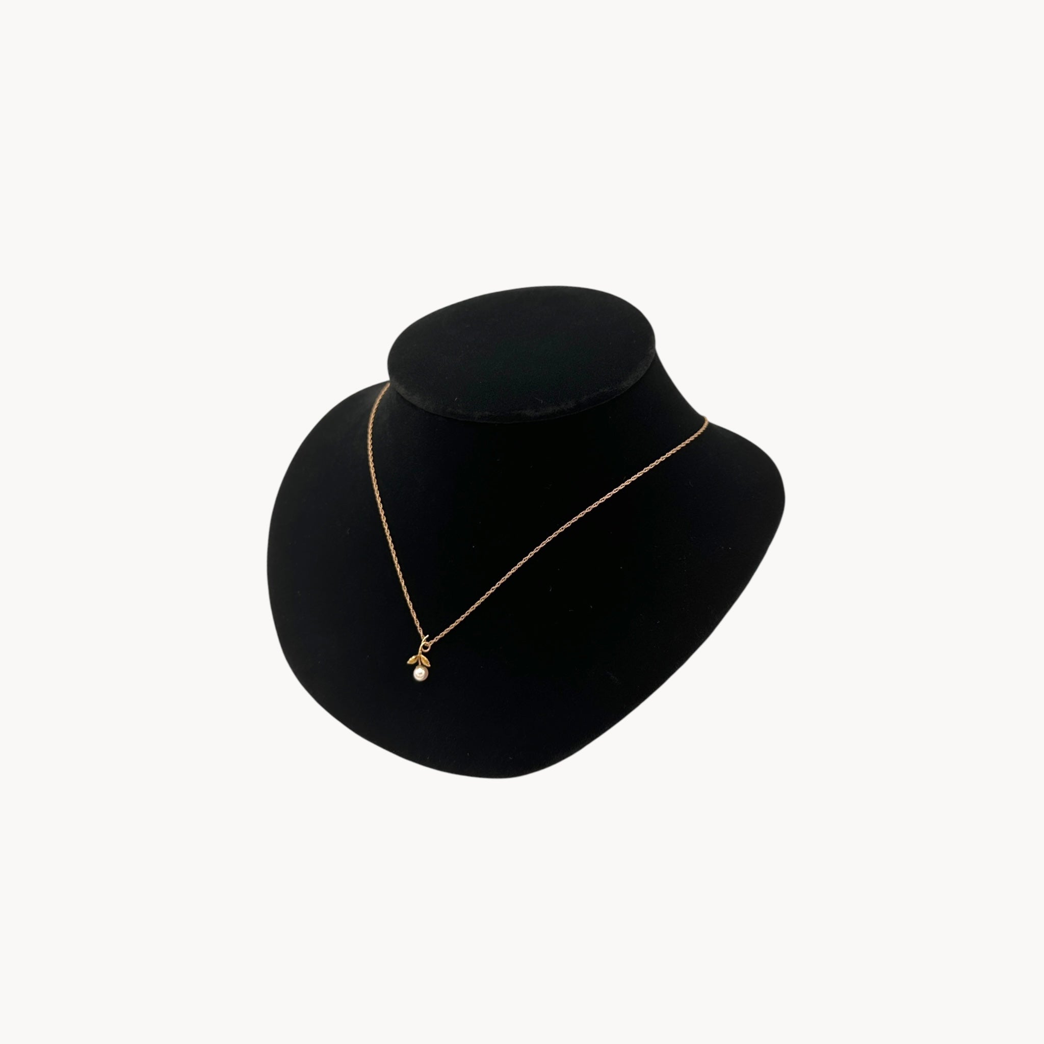 Side view of Krementz dainty gold flower pendant necklace with pearl center.
