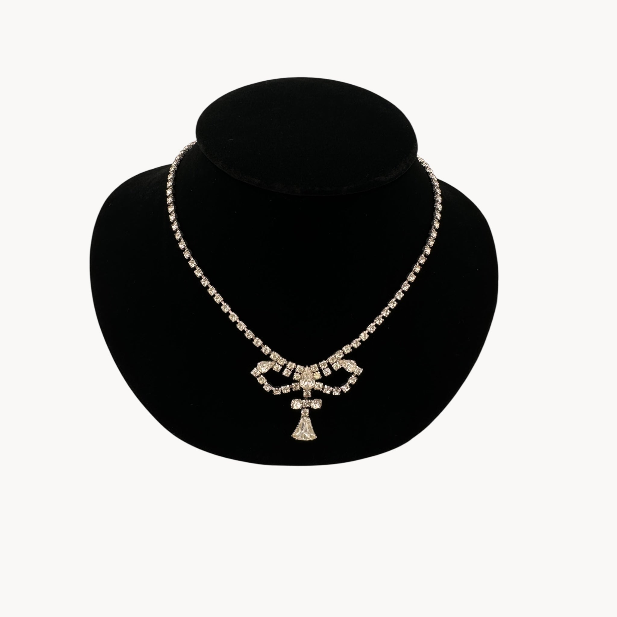 Close up view 1950s Leo Glass rhinestone necklace with bow centerpiece and teardrop pendant, vintage mid-century bridal jewelry.