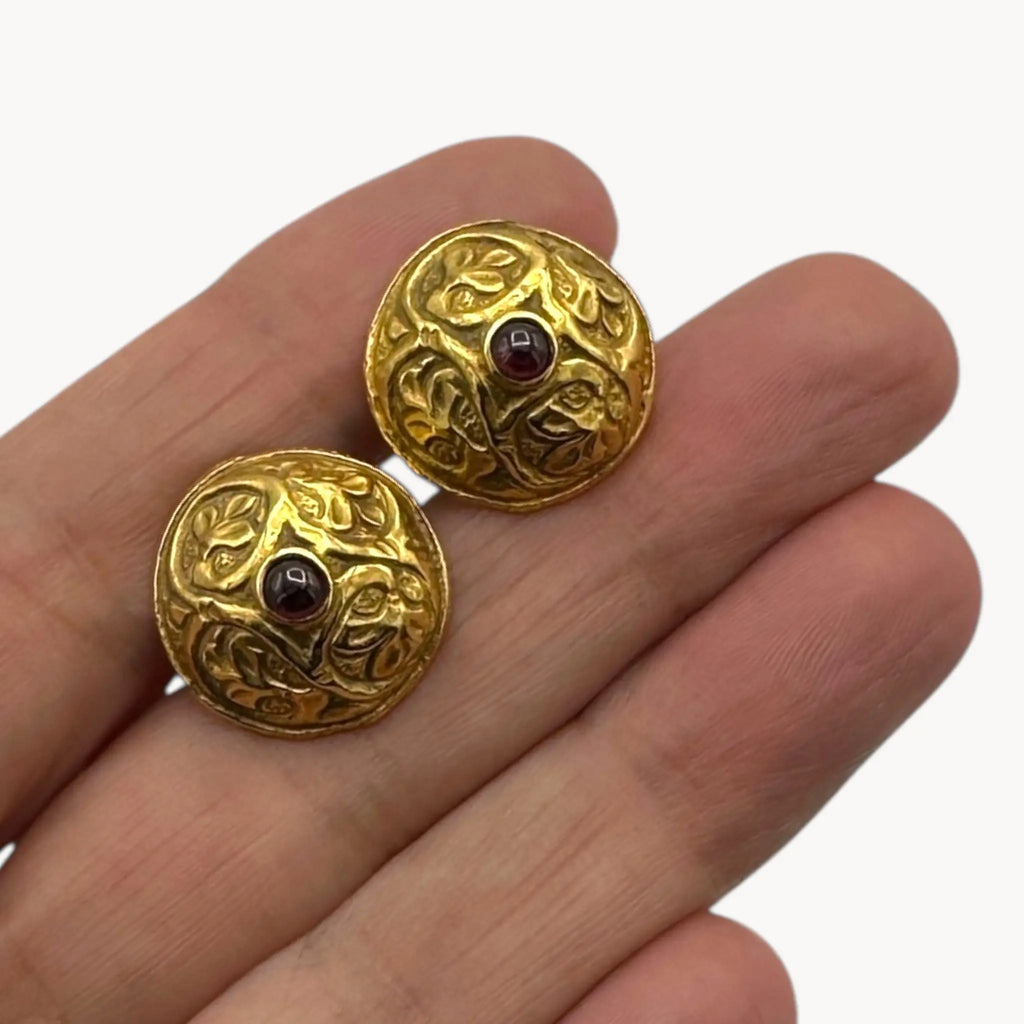 Close up displayed on hand of Vintage MMA gold embossed cufflinks with cabochon centers displayed on white background.