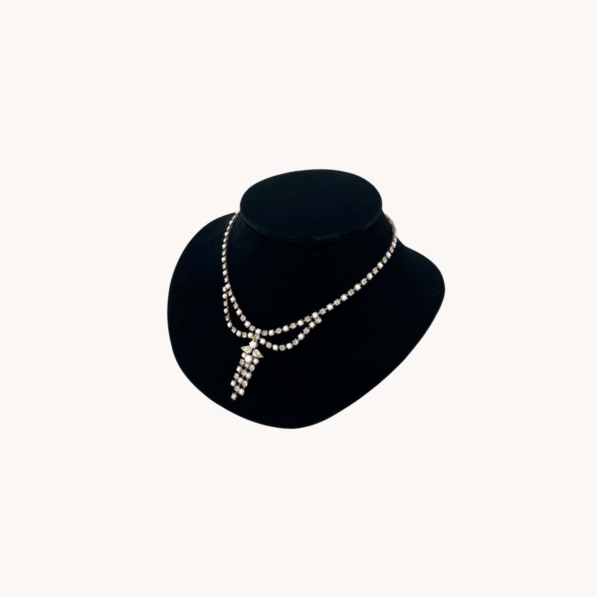 Side view of Vintage mid-century rhinestone and milk glass draped necklace with pendant drop.