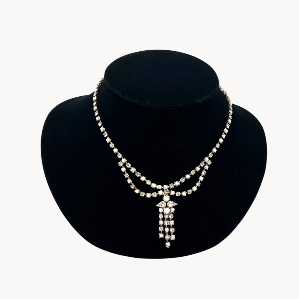 Close up view of Vintage mid-century rhinestone and milk glass draped necklace with pendant drop.