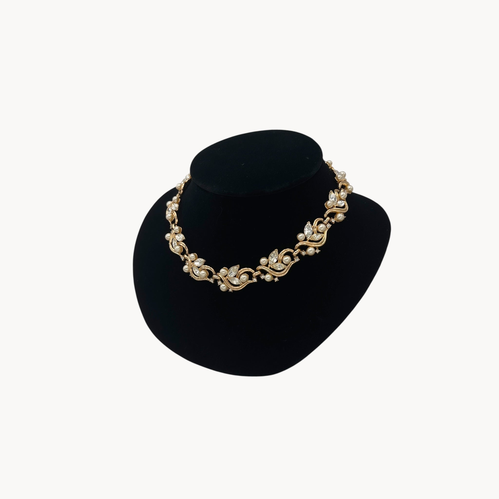 Side view of Midcentury gold floral rhinestone necklace with faux pearls.