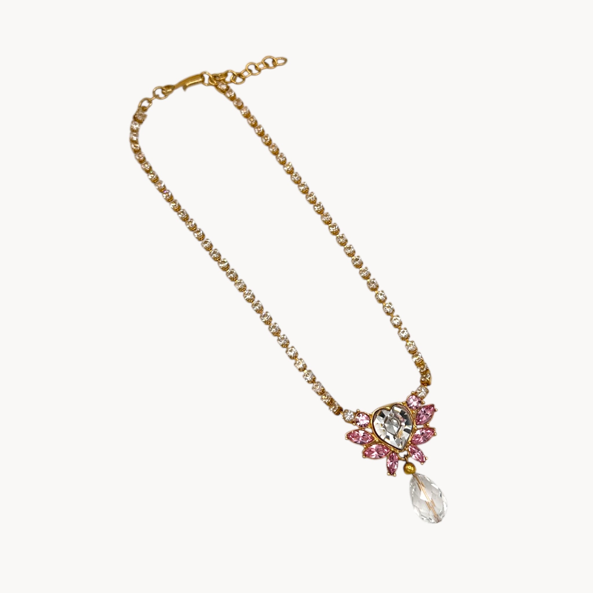 Against white background necklace of Vintage Monet gold necklace and clip-on earring set with clear heart and pink rhinestones.