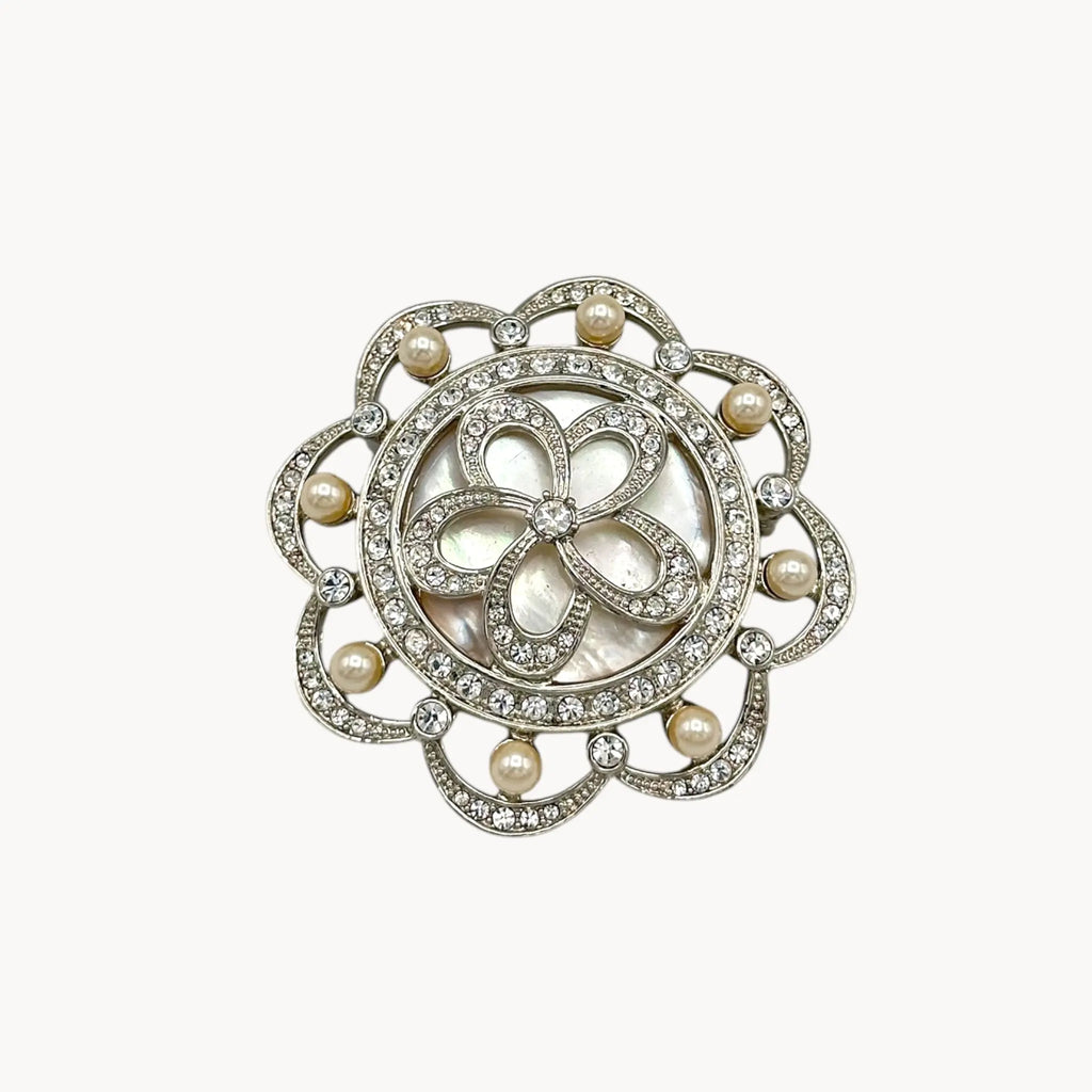 Close up view of Monet vintage silver tone brooch with rhinestones and faux pearls in floral design, elegant bridal jewelry piece on white background.