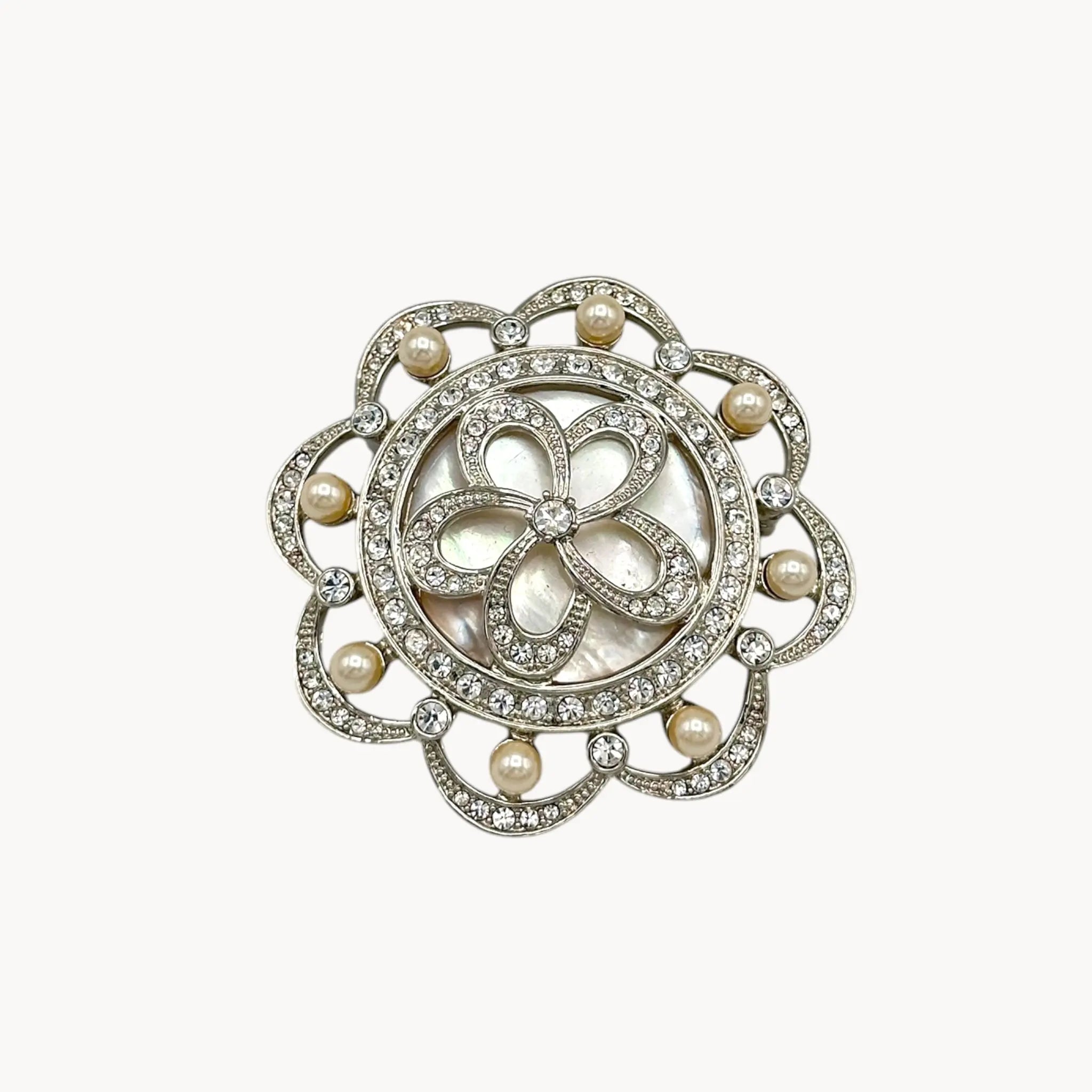 Close up view of Monet vintage silver tone brooch with rhinestones and faux pearls in floral design, elegant bridal jewelry piece on white background.