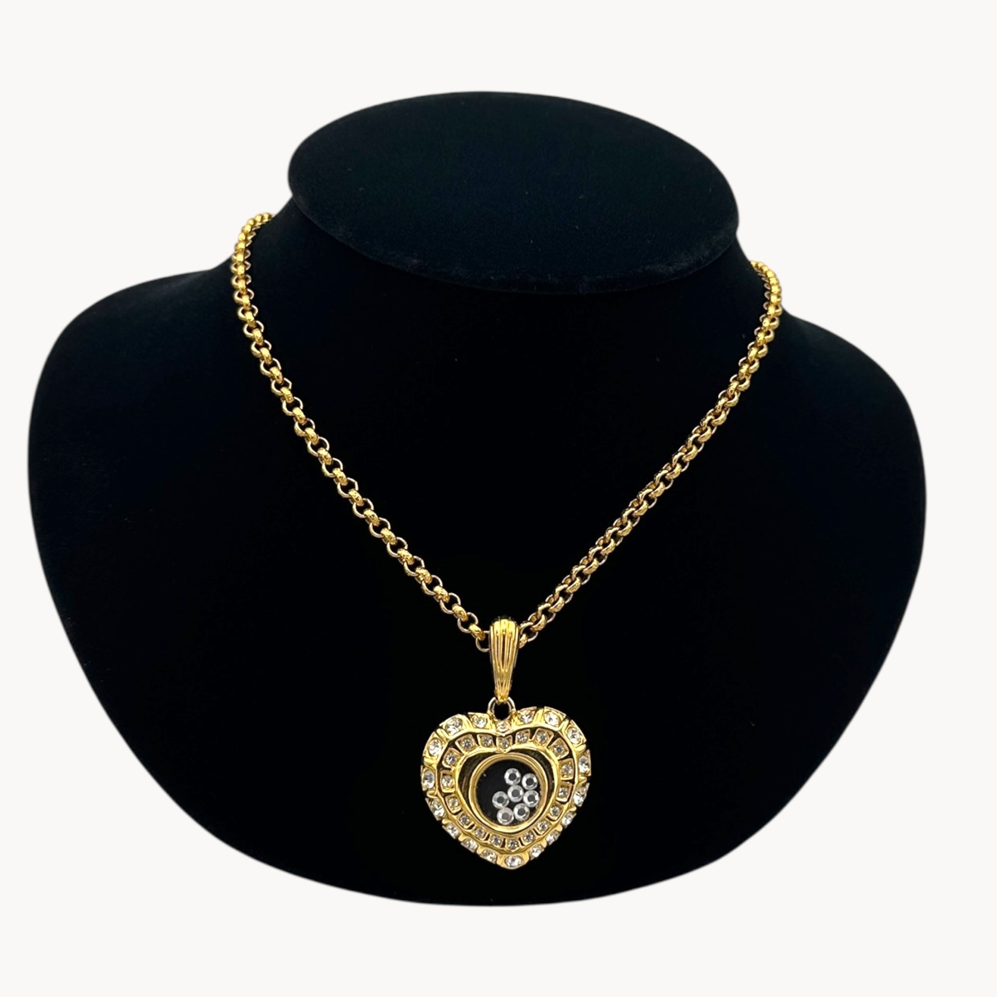 Close up view of Nolan Miller gold-tone heart pendant necklace with clear rhinestones on long chain on black bust.