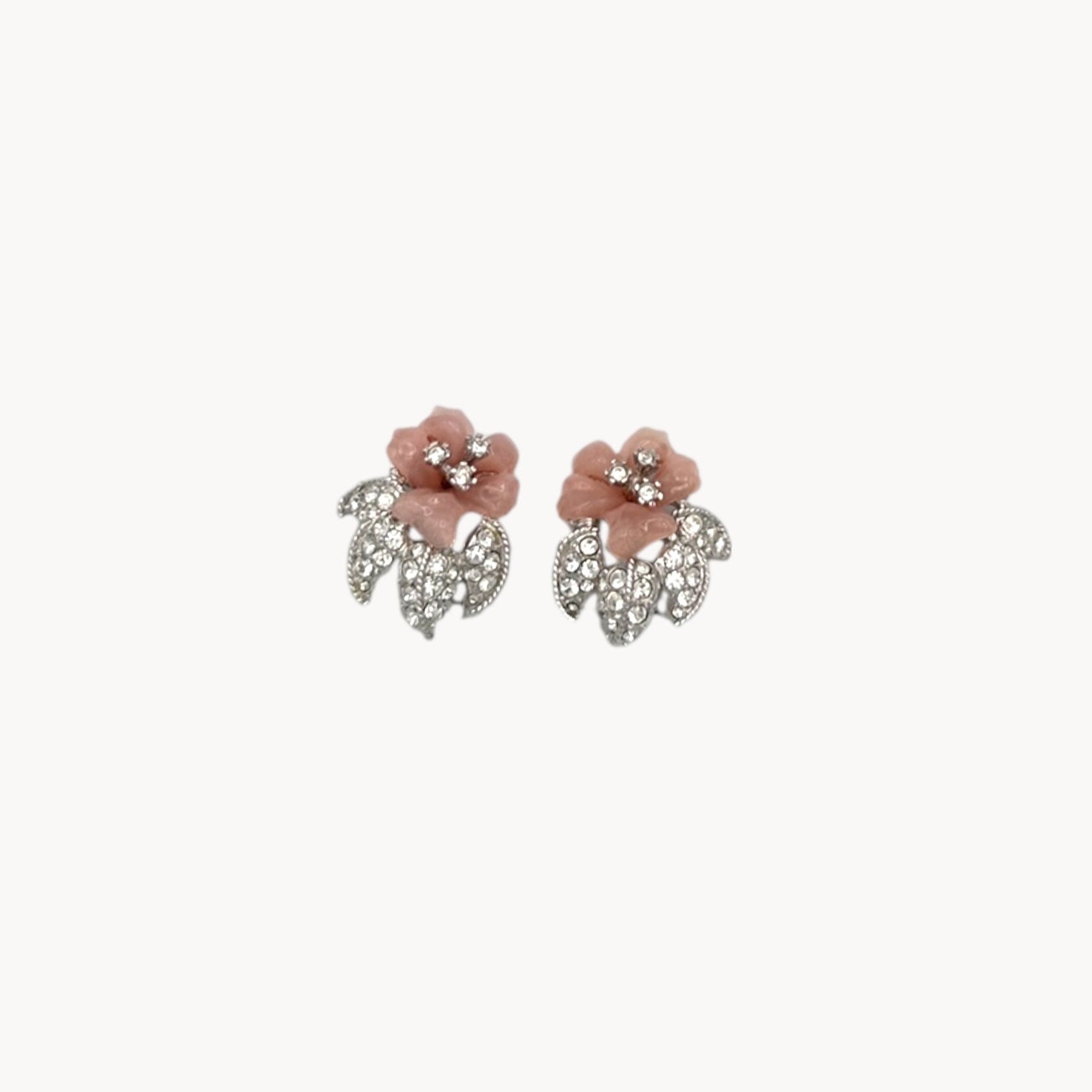 Close up view Nolan Miller vintage pink flower clip-on earrings with rhinestone accents and silver-tone leaves