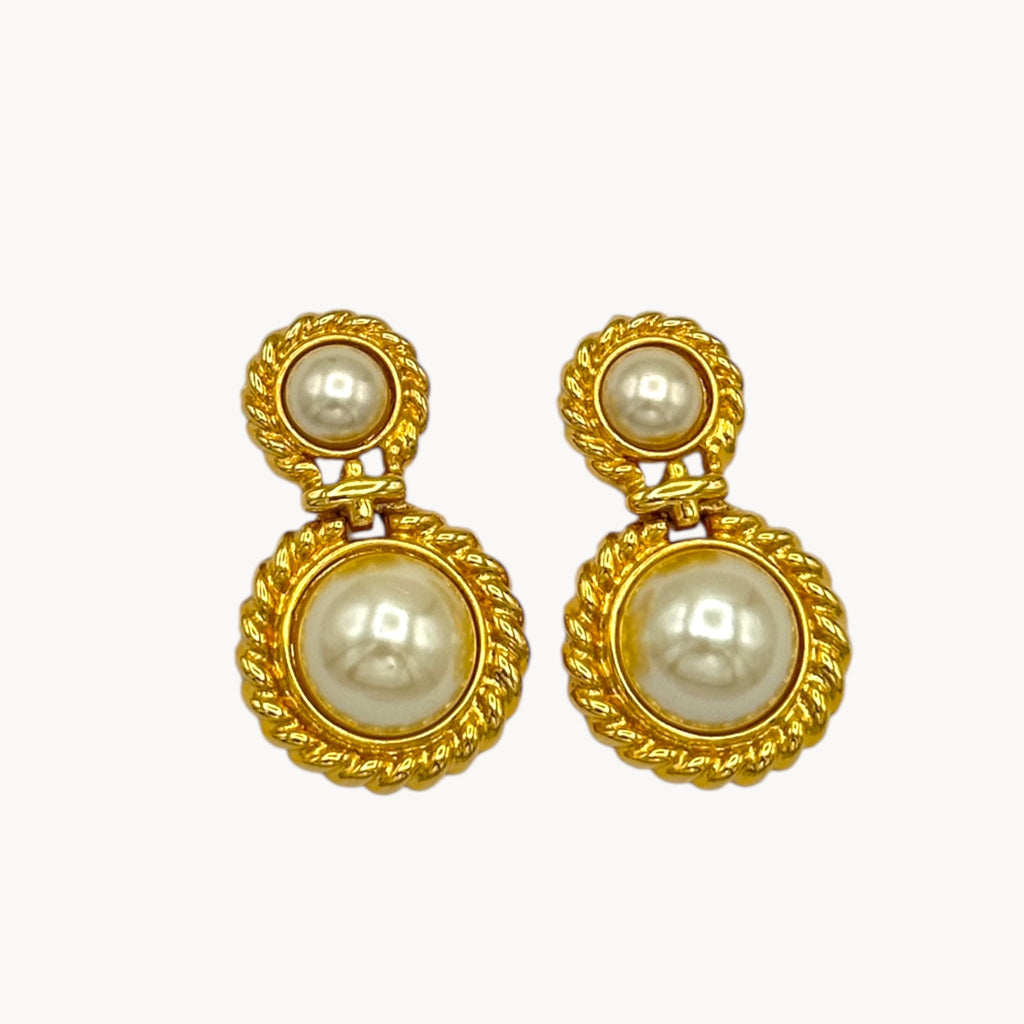 Close up view of Vintage Paquette gold rope dangle earrings with faux pearls on white background.