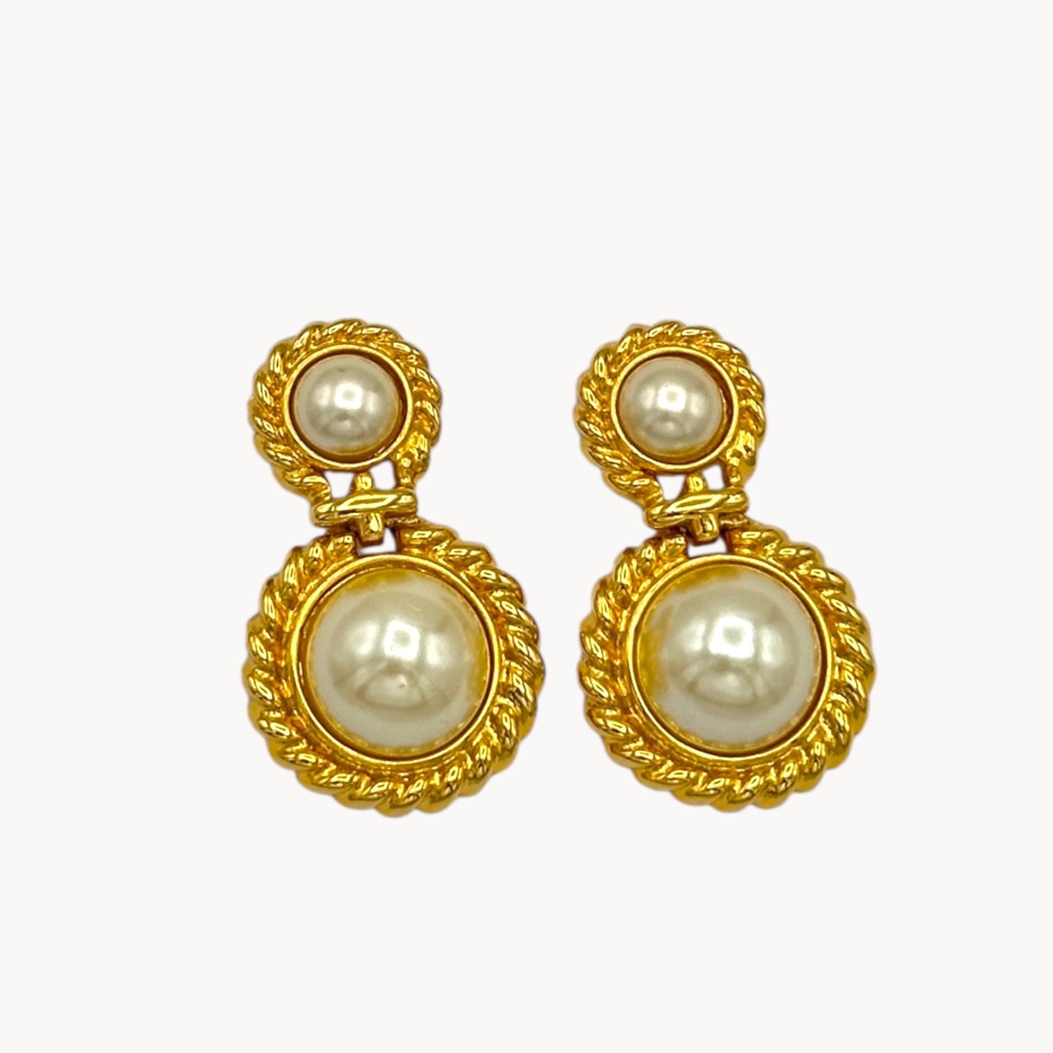 Close up view of Vintage Paquette gold rope dangle earrings with faux pearls on white background.