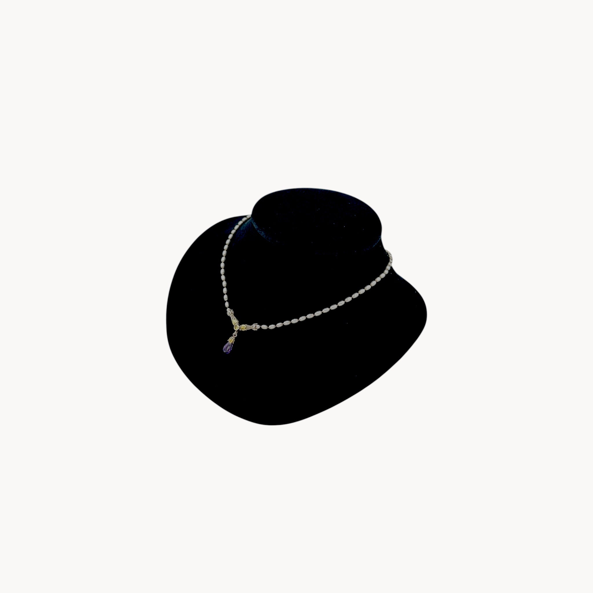 Side view of Sterling silver and 14K yellow gold necklace with amethyst teardrop pendant on black bust.