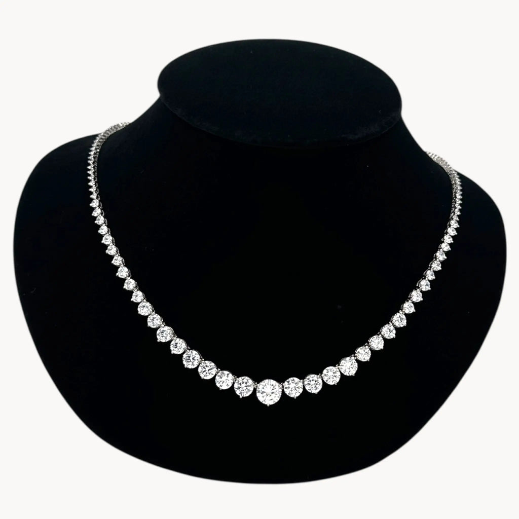 Close up view of Sterling silver rhodium-plated graduated tennis necklace with round-cut stones on black bust.