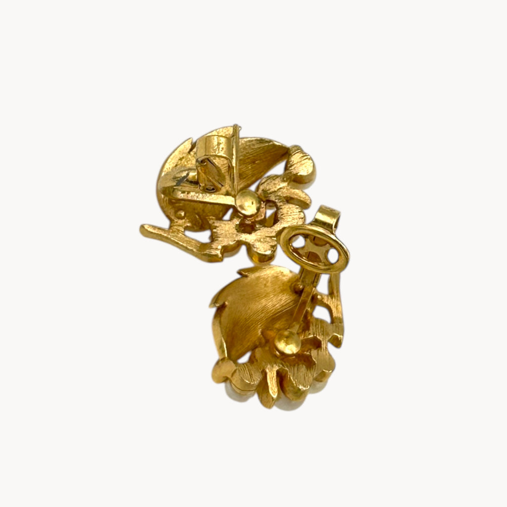 Clips up on Vintage Trifari gold leaf clip-on earrings with faux pearl clusters, mid-century jewelry on white back background.