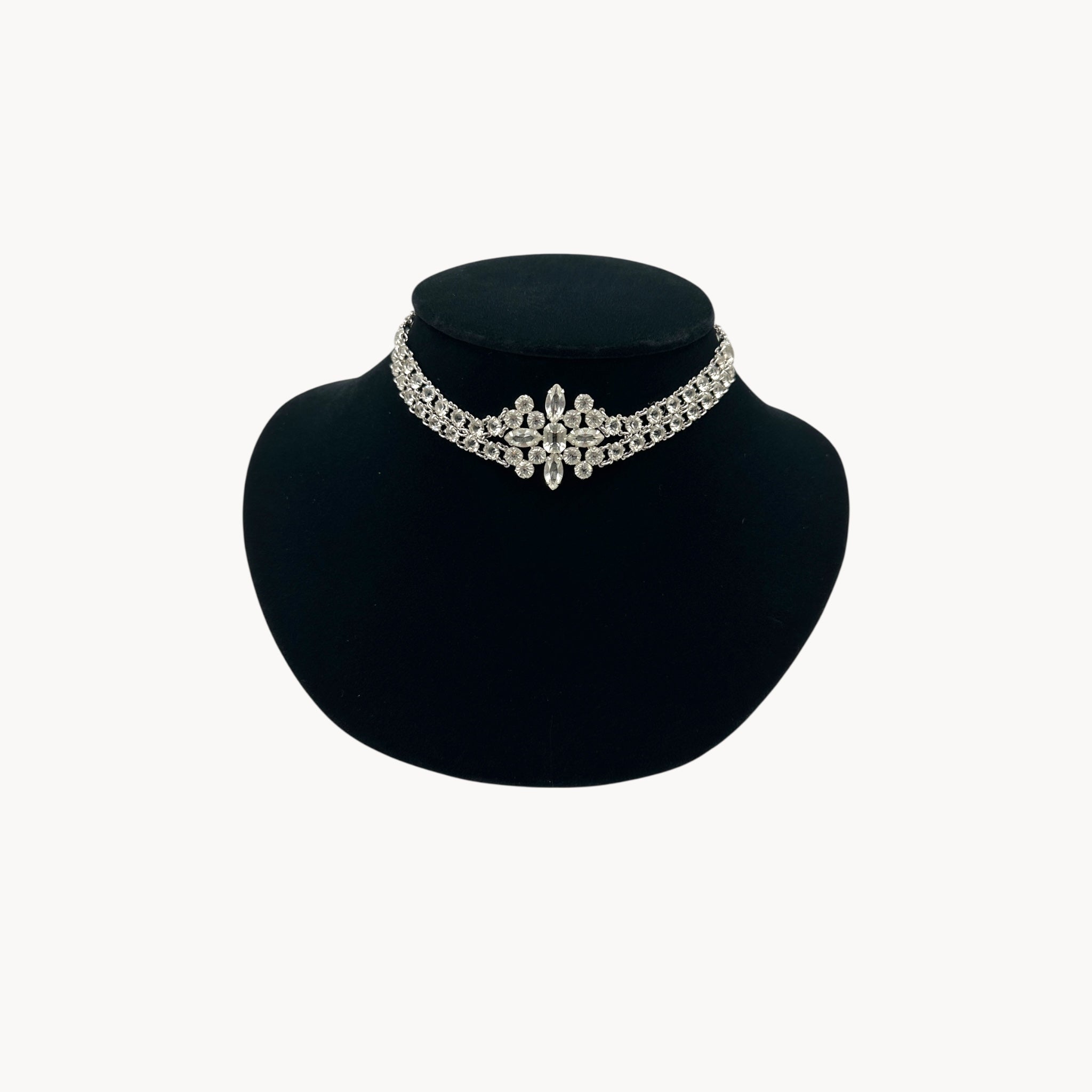 Silver necklace on a black mannequin bust against a white background