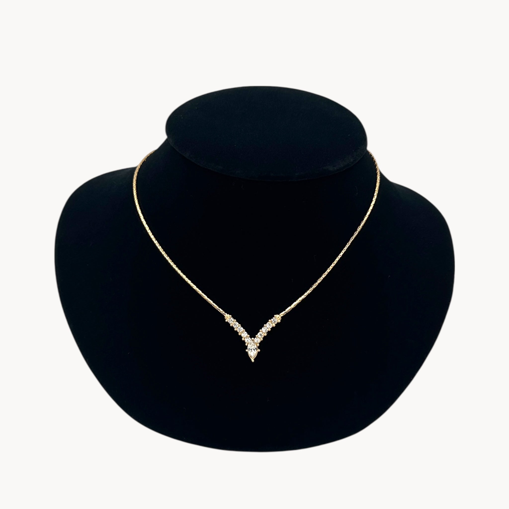 Close up Vintage Christian Dior necklace with gold-tone chain and V-shaped crystal pendant, 1990s bridal jewelry.
