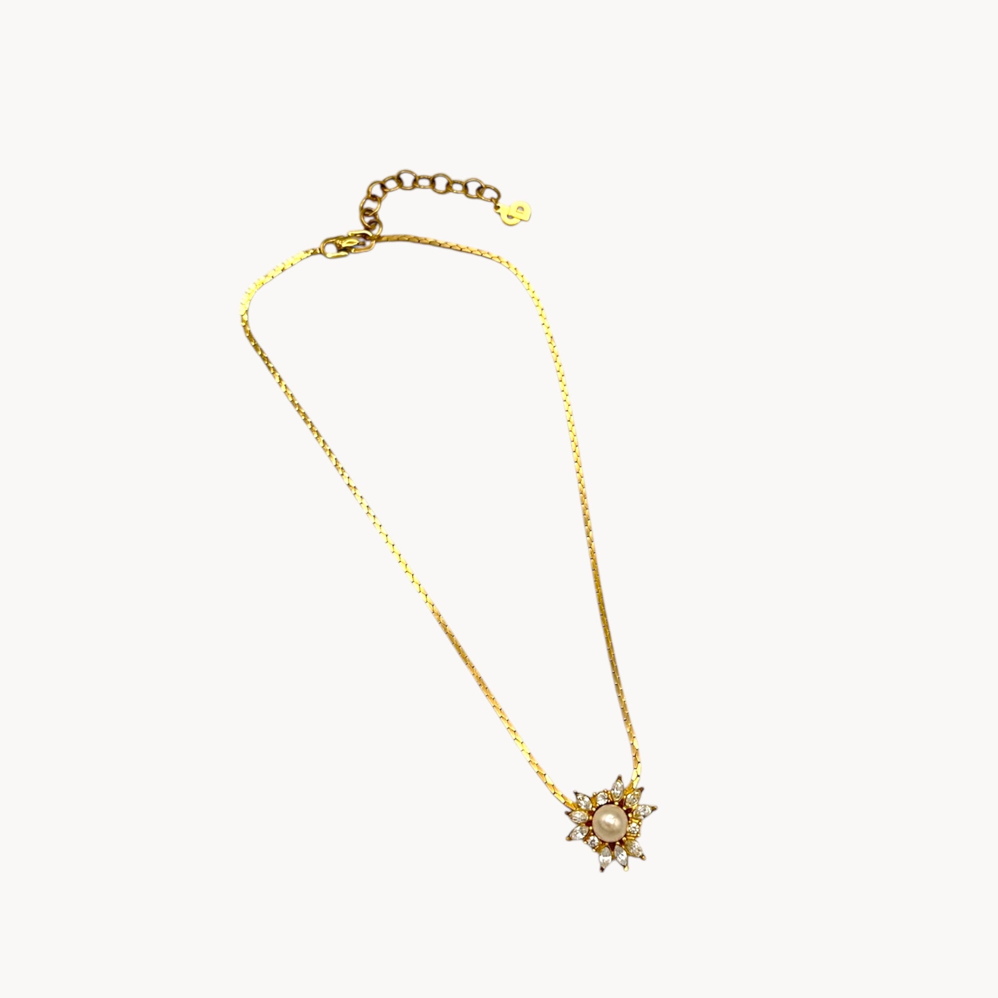Full view Vintage Christian Dior necklace with gold-tone chain and starburst pendant featuring pearl center and crystal accents, 1980s bridal jewelry.