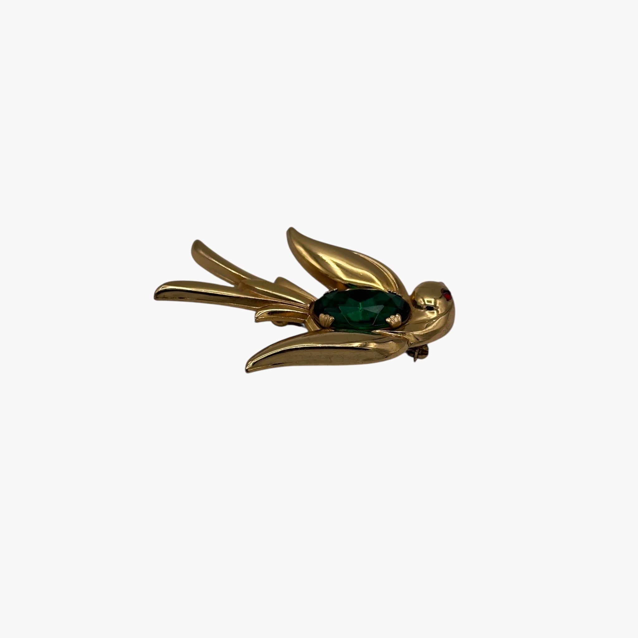Side view Vintage Coro gold-tone bird brooch with green glass stone body and red eye accent, 1950s whimsical bridal accessory.