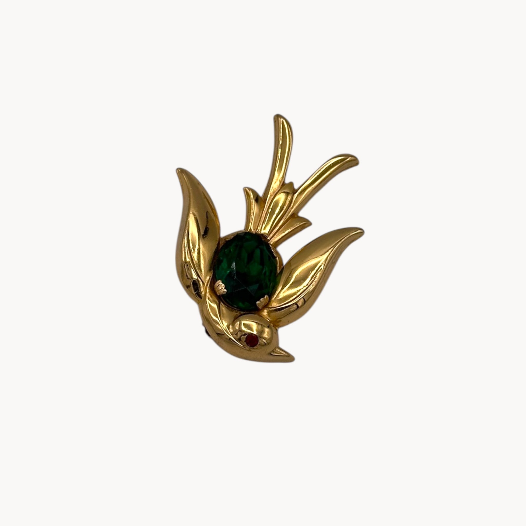 Downward view Vintage Coro gold-tone bird brooch with green glass stone body and red eye accent, 1950s whimsical bridal accessory.