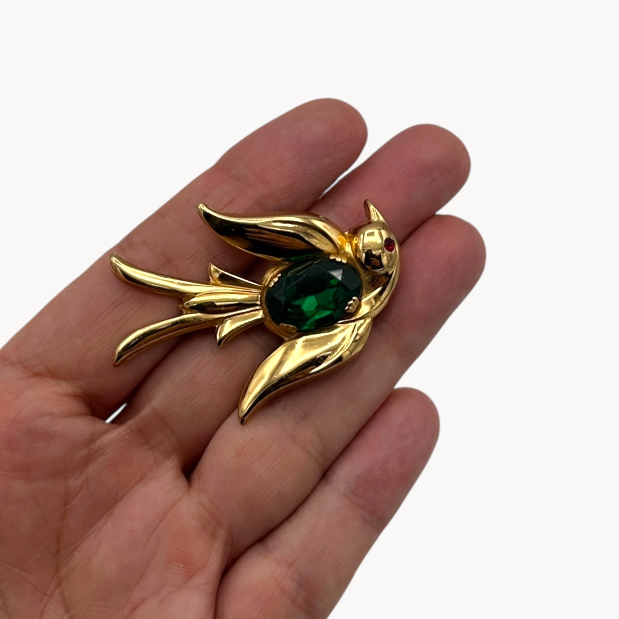 Size scale view Vintage Coro gold-tone bird brooch with green glass stone body and red eye accent, 1950s whimsical bridal accessory.