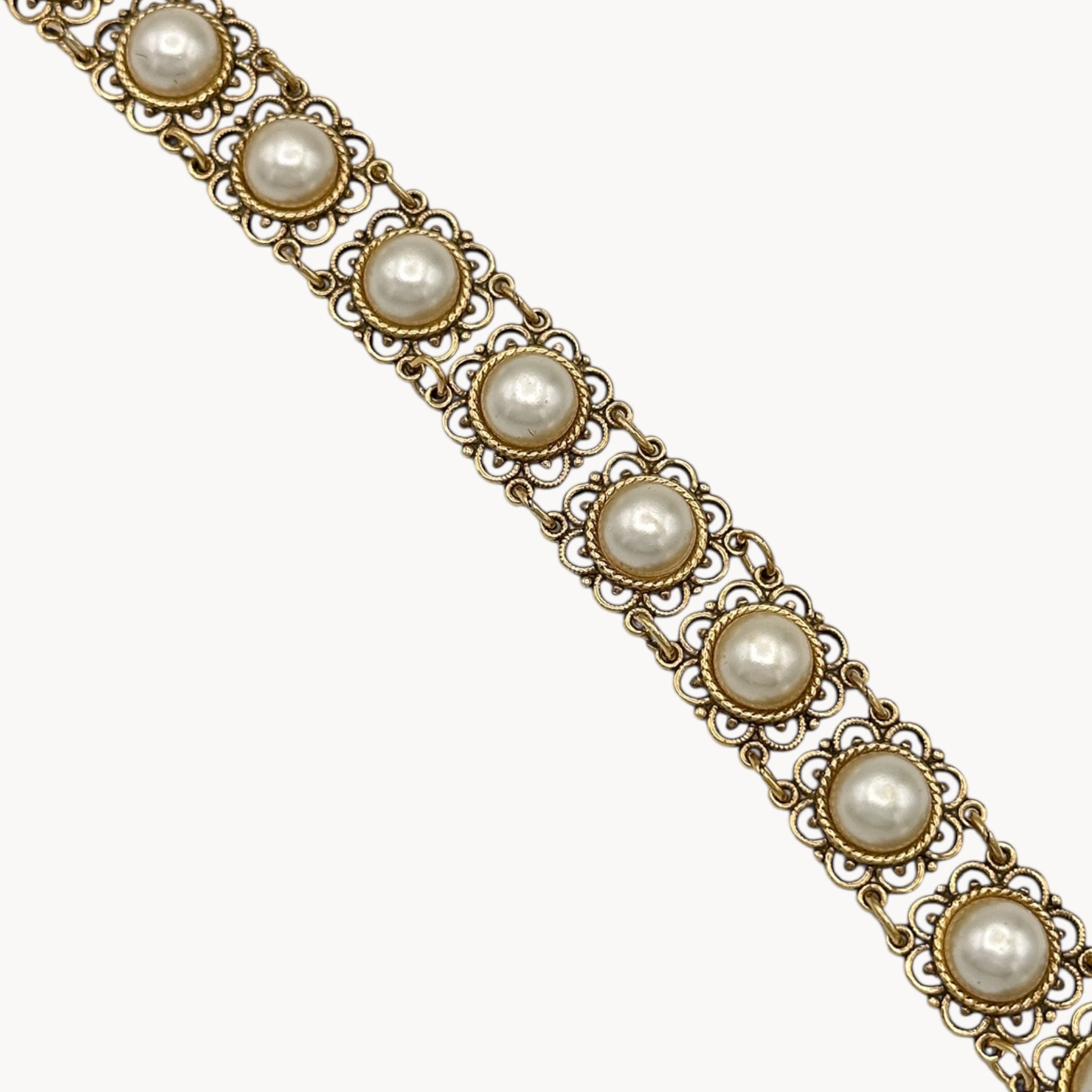 Close up view of Vintage Faux Pearl & Gold Filigree Bracelet on black pillow.