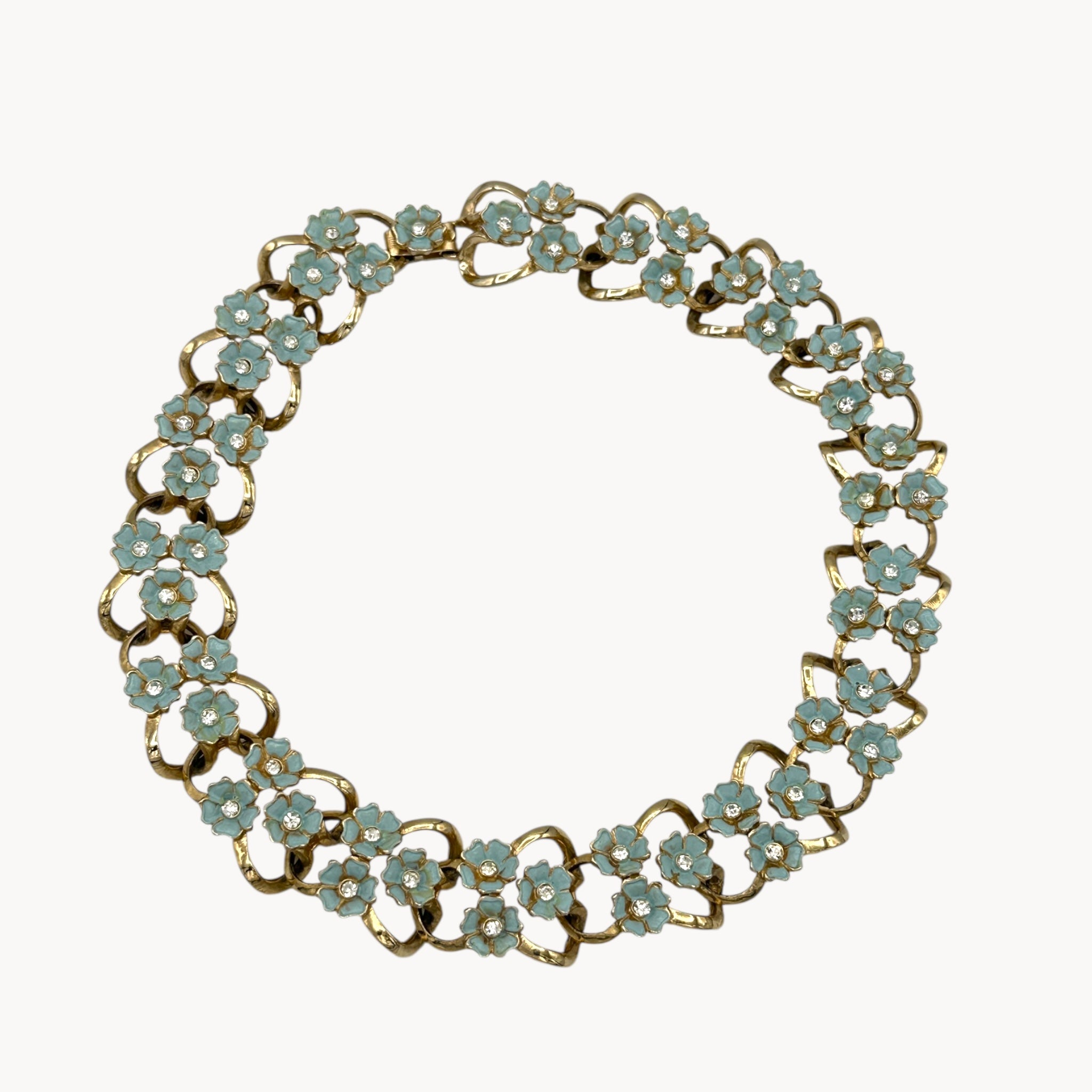 Necklace against white of Vintage mid-century forget-me-not floral necklace and earring set with blue enamel flowers and rhinestones, 1950s bridal jewelry.