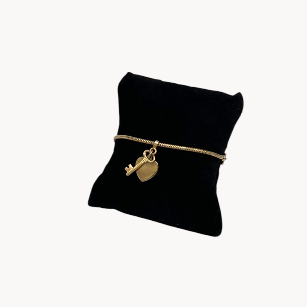 Close up view of Vintage gold-filled snake link bracelet with sliding heart and key charm, romantic mid-century jewelry.