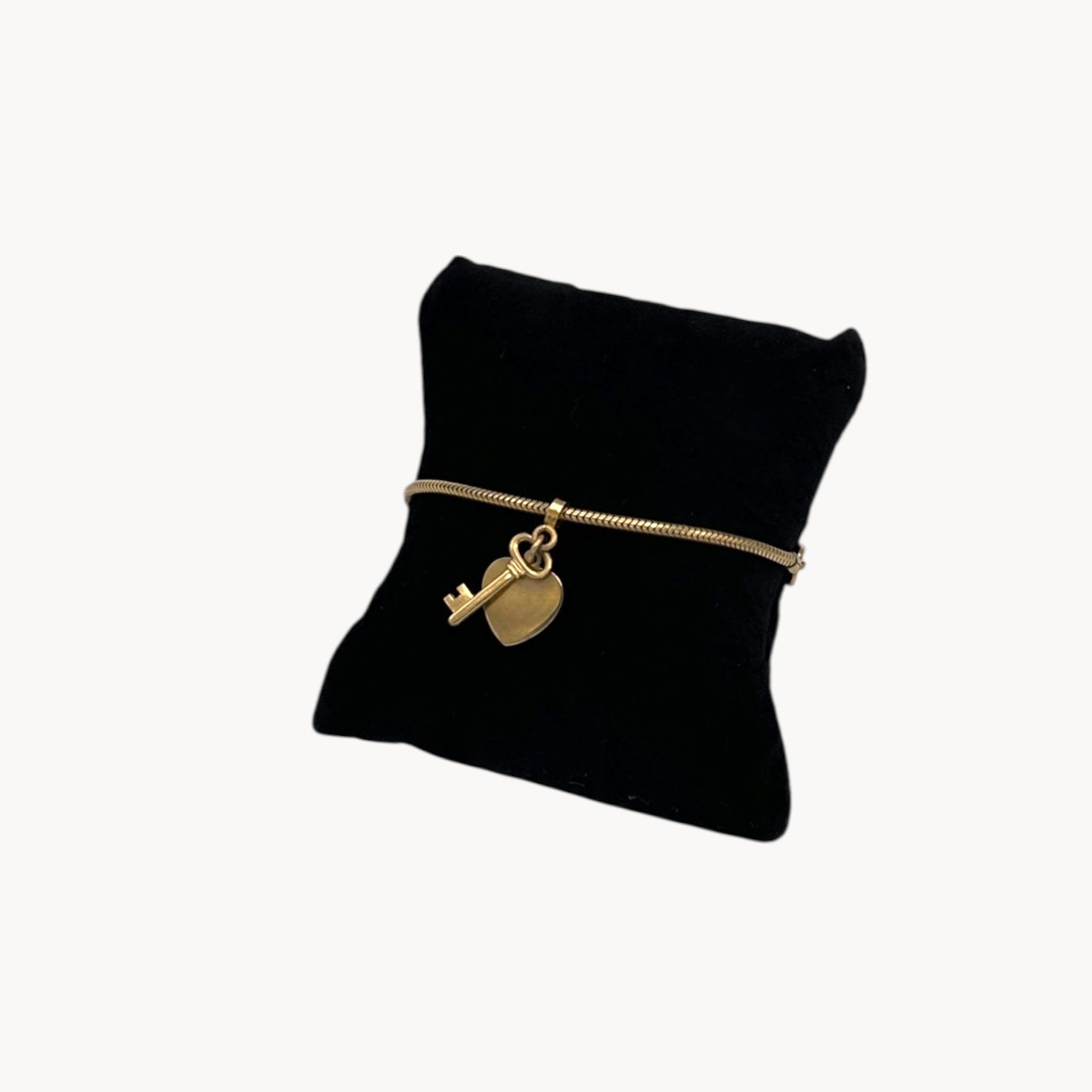 Close up view of Vintage gold-filled snake link bracelet with sliding heart and key charm, romantic mid-century jewelry.