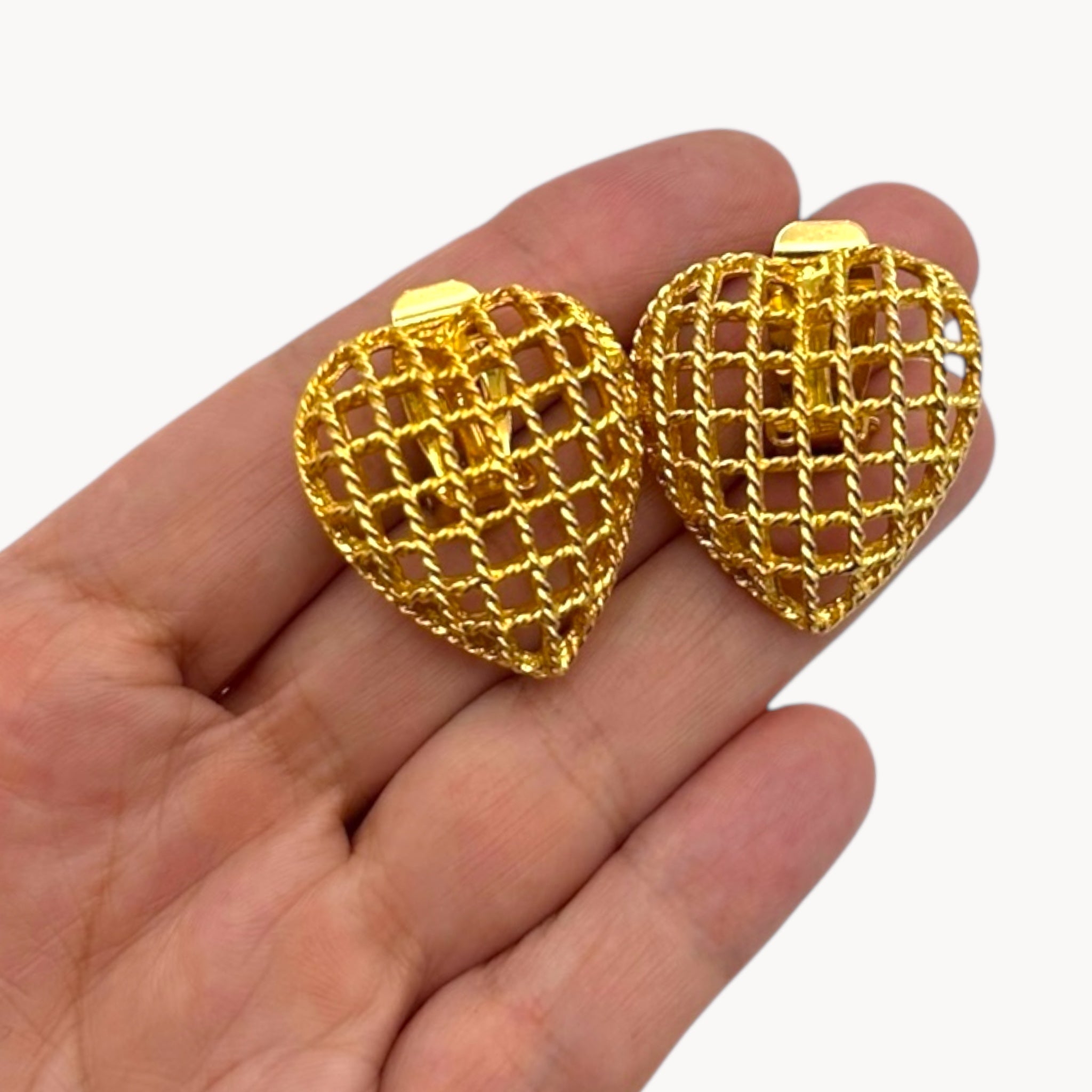 Earrings on hand of Bracelet of Vintage gold caged pearl heart bracelet and matching clip-on earrings set, 1980s–1990s jewelry on white background.