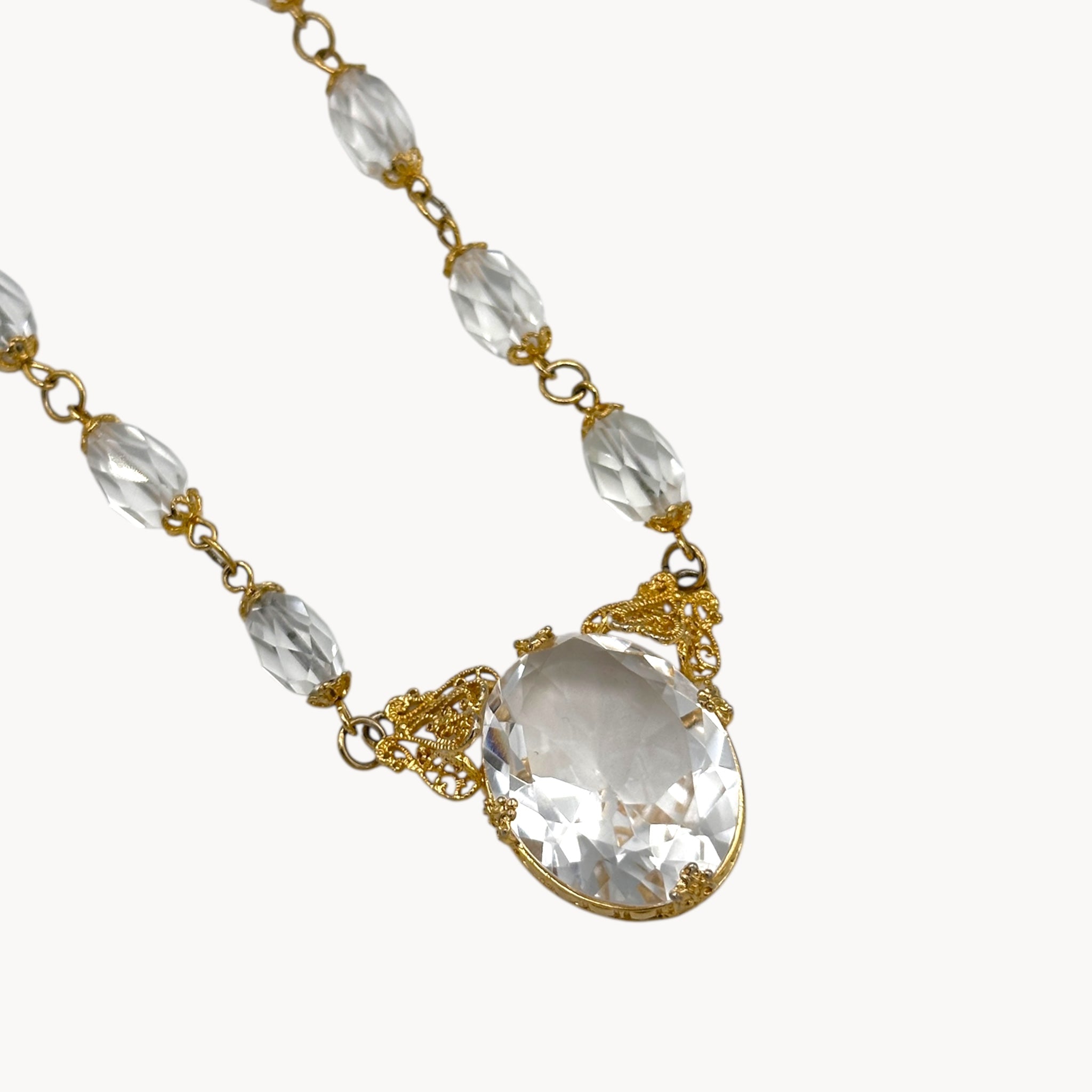 Close up view of Necklace with clear beads and a large crystal pendant on a white background